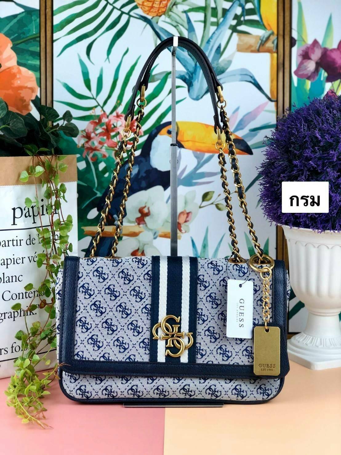 Guess Logo city handbag กระเป๋าสะพายไหล่ ตัวกระเป๋าเป็นผ้าลาย signature ของแบรนด์ ตัดกับหนังที่ตัวขอบกระเป๋า มาพร้อมพวงกุญแจโลโก้แบรนด์ ด้านหน้ามีโลโก้แบรนด์ ด้านหลังมีช่องใส่โทรศัพท์/บัตรได้ เปิดปิดแบบกระดุมแม่เหล็กซ้าย-ขวา ด้านในมีช่องซิป เล็ก 1 ช่อง แล