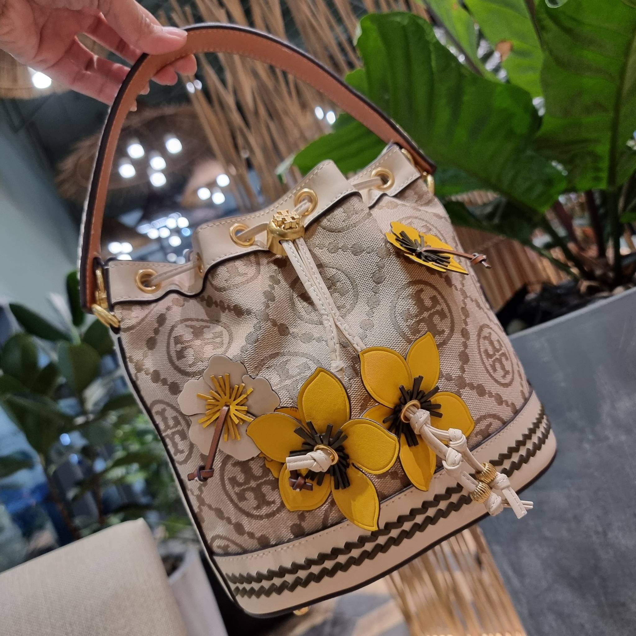 TORY BURCH T MONOGRAM FLORAL BUCKET BAG คอลเลคชั่นใหม่ พร้อมเสิร์ฟความสวยให้ถึงบ้าน!! กระเป๋าบัคเก็ตทรงยอดนิยม ดีไซน์ใหม่ล่าสุด สไตล์งานคราฟ มีลูกเล่นประดับดอกไม้กับตัวกระเป๋า และตัวรูดสาย วัสดุผ้า jacquard ตัดสลับหนังแท้ หูจับและขอบกระเป๋าตกแต่งลายสานสวย