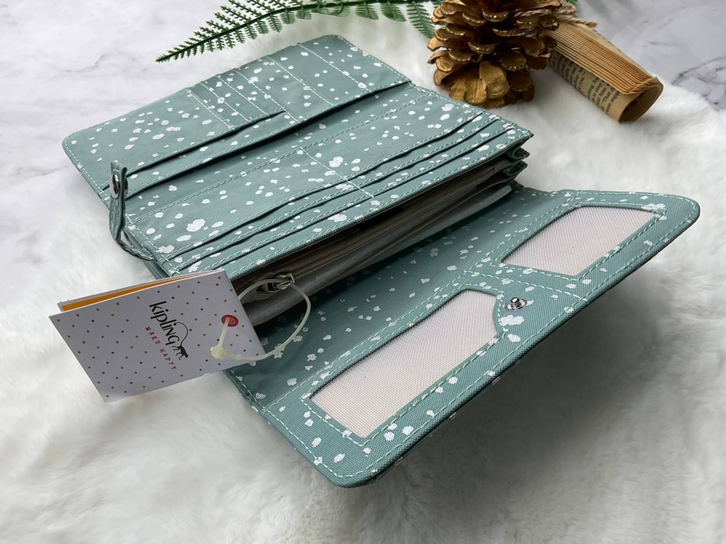 กระเป๋าสตางค์ยาว 3 พับตอน Kipling Brownie long tri-fold wallets กระเป๋าสตางค์ยาวแบบ3พับตอน วัสดุกันน้ำ เปิดปิดด้วยกระดุมแป๊ก มีช่องใส่ธนบัตรหลายช่อง ช่องเสียบการด์ได้ถึง13ช่องลายจุด และใส่รูปภาพได้อีก2ช่อง ช่องซิปใส่เหรียญ ช่องธนบัตร 3 ช่อง ที่จับหัวซิปปั