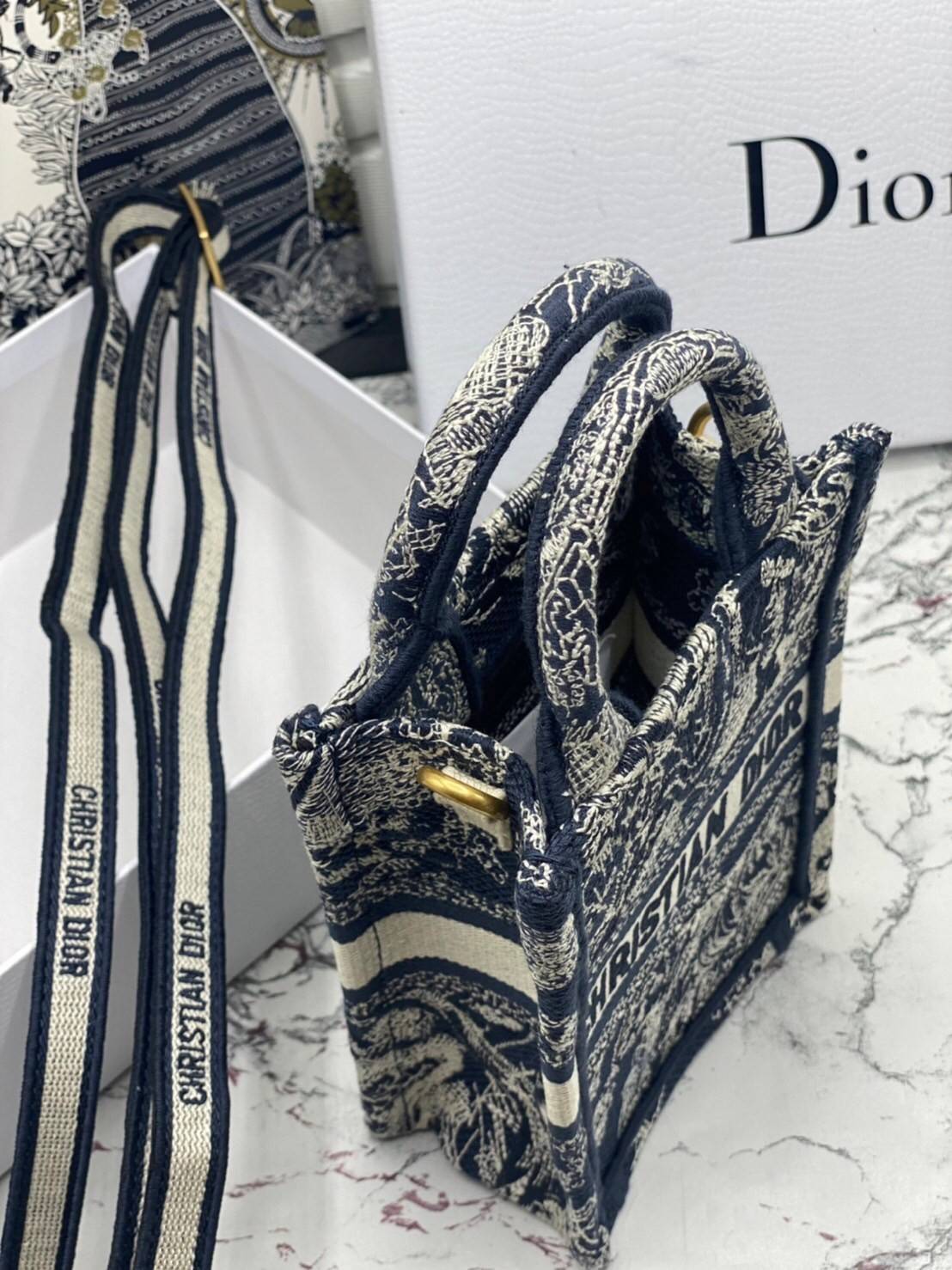 ORI 】Mini Dior Book Tote Phone Bag พร้อมส่งที่ไทย ภาพสินค้าถ่ายจากงานขายจริง ใช้งานต่างประเทศได้ กระเป๋าใบมินิจะใส่โทรศัพท์ได้เช่นเดียวกับของใช้จำเป็นเล็กๆ น้อยๆ ในแต่ละวัน มาพร้อมสายสะพายไหล่แบบปักที่ปรับได้และถอดออกได้ อุปกรณ์เสริมอันทันสมัยนี้สามารถสวม