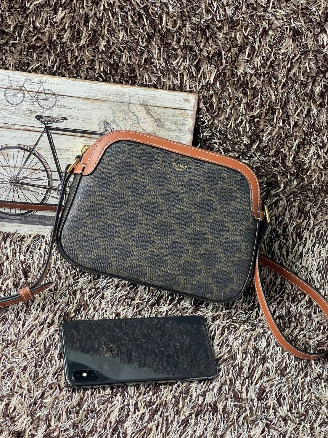 CELINE Triomphe Canvas Small Camera กระเป๋าสะพายไหล่สุดเก๋ใบนี้ผลิตจากผ้าใบเคลือบอย่างดีพร้อมขอบหนังสีน้ำตาล มาพร้อมสายสะพายหนังปรับระดับได้พร้อมฮาร์ดแวร์สีทองและซิปด้านบน ภายในบุด้วยผ้าสีน้ำตาล ลวดลาย triomphe อันเป็นเอกลักษณ์ของแบรนด์ และเป็นกระเป๋าสะพา