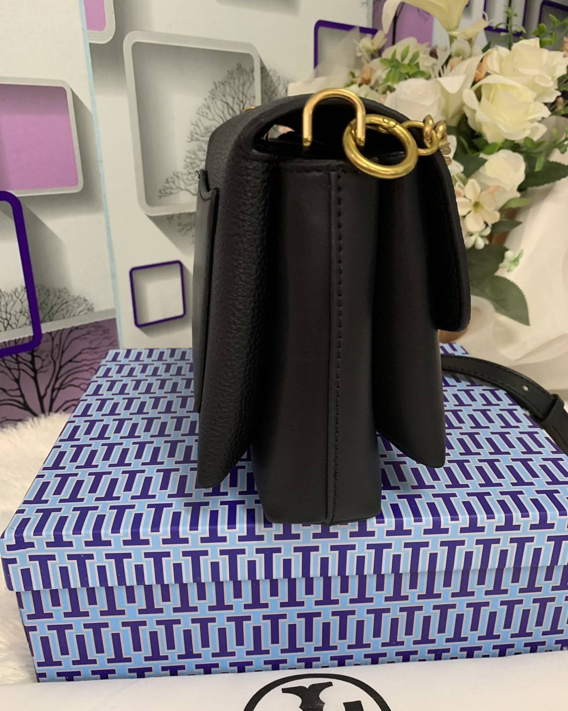 TORY BURCH KIRA MIXED-MATERIALS TOP-HANDLE SATCHEL กระเป๋าสะพายข้าง วัสดุหนังแกะสังเคราะห์ อะไหล่ทอง ด้านหน้าประดับโลโก้แบรนด์ ตกแต่งสายโซ่ห้อยสีทอง (สามารถถอดออกได้) เปิด-ปิดด้วยตัวล็อคหมุน ภายในโล่งกว้าง ซับในบุผ้าลายแบรนด์ แบ่งออกเป็น 3 ช่องใหญ่ พร้อมช