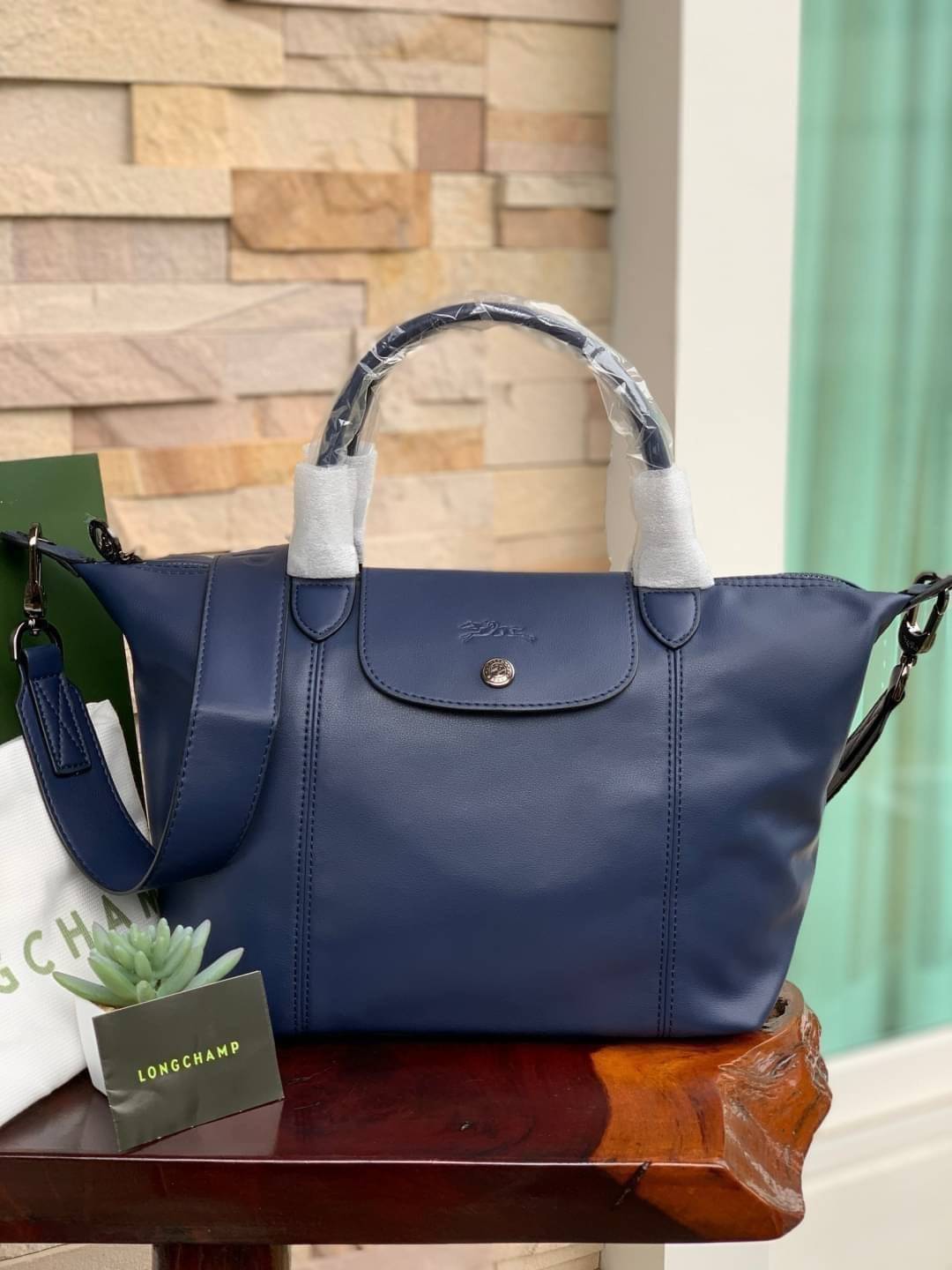 Longchamp LE PLIAGE CUIR TOP HANDLE BAG S เรียกว่าเป็นกระเป๋าอีกหนึ่งรุ่นที่ไม่ว่ายังไงก็ฮอตฮิตและติดเทรนด์ตลอดไม่เคยเปลี่ยนกับ ทรง Le Pliage Cuir หนึ่งในตระกูลกระเป๋าสุดไอคอนิกจากแบรนด์ เมื่อรุ่น Le Pliage Cuir ในรูปแบบของหนังแกะ Metis ได้ถือกำเนิดขึ้นใน