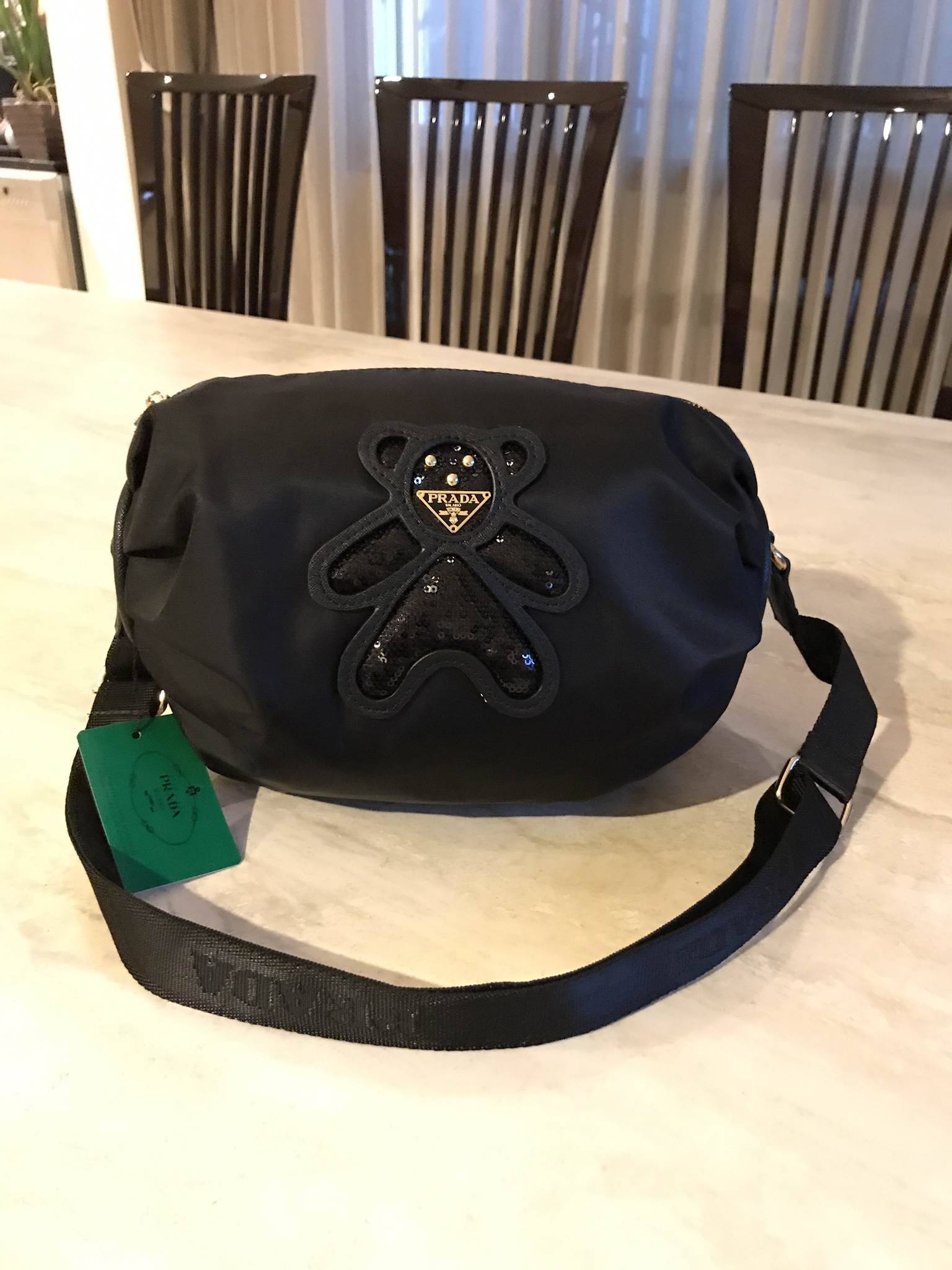 มาแล้วค้า! PRADA NYLON CROSSBODY BAG กระเป๋าสะพายพรีเมี่ยมกิ้ฟจากเคาน์เตอร์ต่างประเทศ Limited edition วัสดุ Nylon เนื้อหนาคุณภาพดีตามแบบฉบับแบรนด์ ขนาดใหญ่ จุได้เยอะ น้ำหนักเบา ด้านหน้าเป็นลายหมีปั๊กกลิ้ตเตอร์โลโก้แบรนด์อะไหล่ทองหรู ภายในซับ Polyester 100