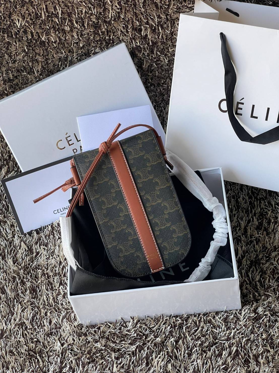 Celine Phone Pouch in Triomphe Canvas กระเป๋าใส่โทรศัพท์รุ่นนี้ มีดีไซน์ดูเรียบง่าย แต่ดูหรูหราด้วยลวดลาย Triompe ที่แสดงถึงความเป็นเอกลักษณ์ของ celine ช่องหลักที่มีความกว้าง สามารถใส่โทรศัพท์มือถือ ธนบัตร บัตรต่าง ๆ และของจุกจิกชิ้นเล็ก ๆ ได้แบบจุใจ หรือ