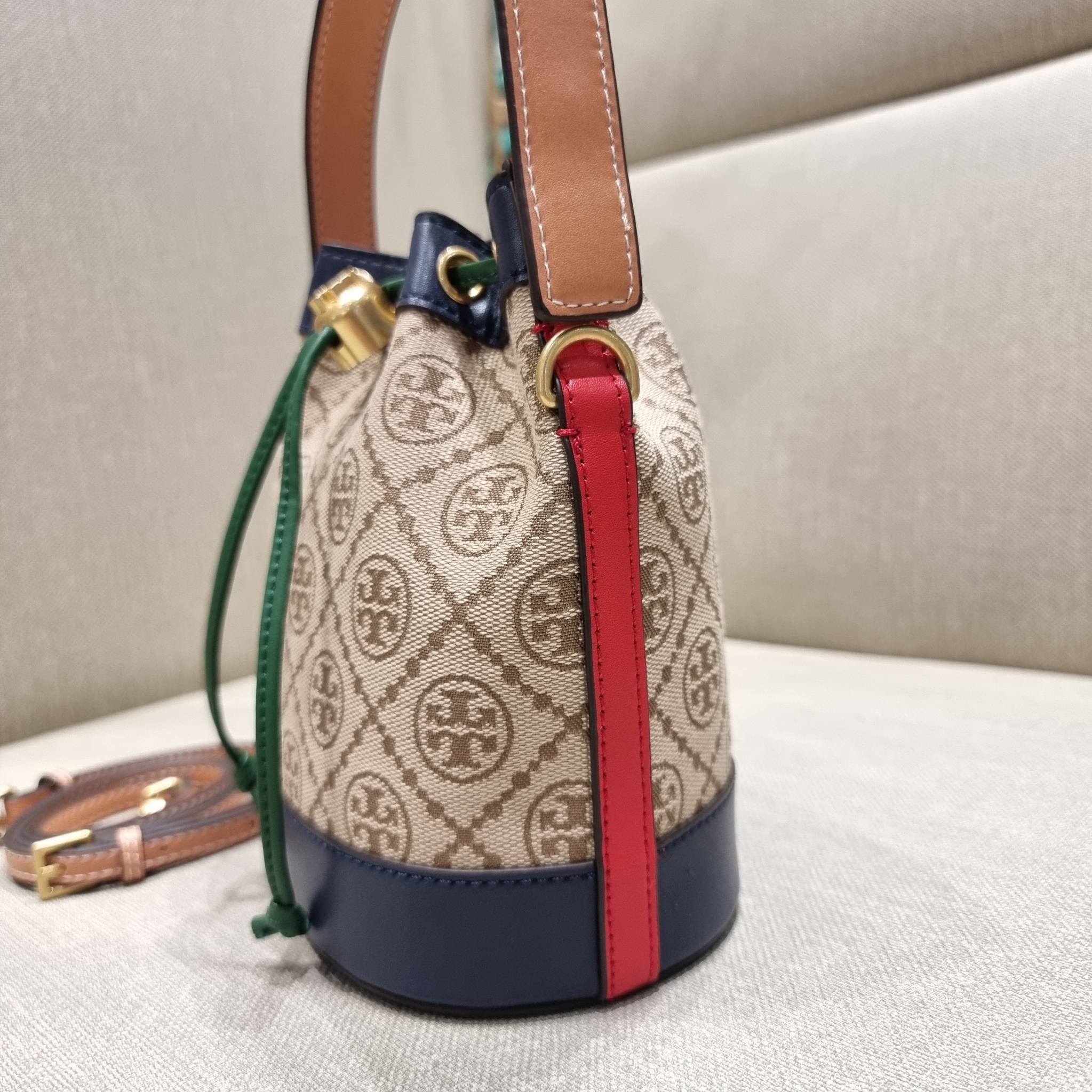 MINI : TORY BURCH T MONOGRAM COLOR-BLOCK JACQUARD MINI BUCKET BAG ใหม่ล่าสุด กับกระเป๋าบัคเก็ตทรงสวย ไซส์มินิ ในราคาน่ารัก โดดเด่นด้วยลวดลายเอกลักษณ์ ผสานลายคัลเลอร์บล็อค โทนสีตัดกันอย่างลงตัว ถักทอบนวัสดุ woven jacquard ลายคมชัด สลับส่วนของหนังแท้ ภายในเ