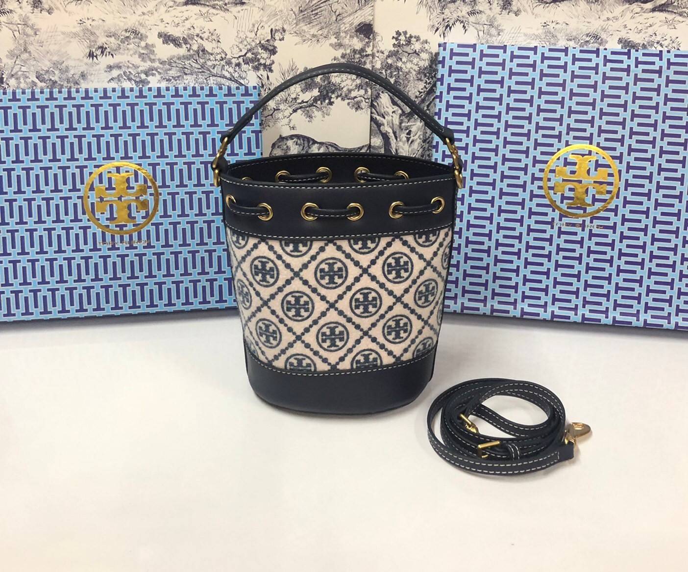 Mini : Tory Burch T Monogram Chenille Bucket Bag เปิดตัวอีกหนึ่งรุ่นกับกระเป๋าลาย T MONOGRAM รุ่นใหม่ล่าสุดจาก TORY BURCH พลาดไม่ได้กับโลโก้สุดคลาสสิก ลวดลาย T Monogram คือวัสดุ chenille หรือที่เรียกว่า ด้านไหมกำมะหยี่ มารังสรรค์ลงบนกระเป๋าBucketใบนี้ เป็