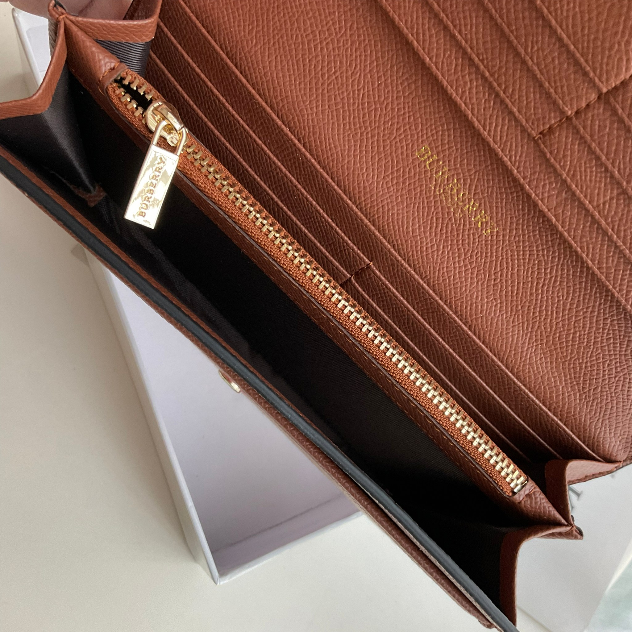 กระเป๋าสตางค์รับทรัพย์ ทรงหรู จากงาพรีเมี่ยมกิ๊ฟ Limited Edition จาก BURBERRY กระเป๋าสตางค์ใบยาวแบบพับกระดุม ทูโทนด้วยหนังแท้คาดผ้าลาย vintage ด้านในมีช่องใส่ธนบัตรยาวทั้งสองฝั่ง ช่องใส่บัตรได้อย่างน้อย 12 ช่อง และช่องเปิดด้วยซิปปั้มแบรนด์อะไหล่ทองสุดหรู 