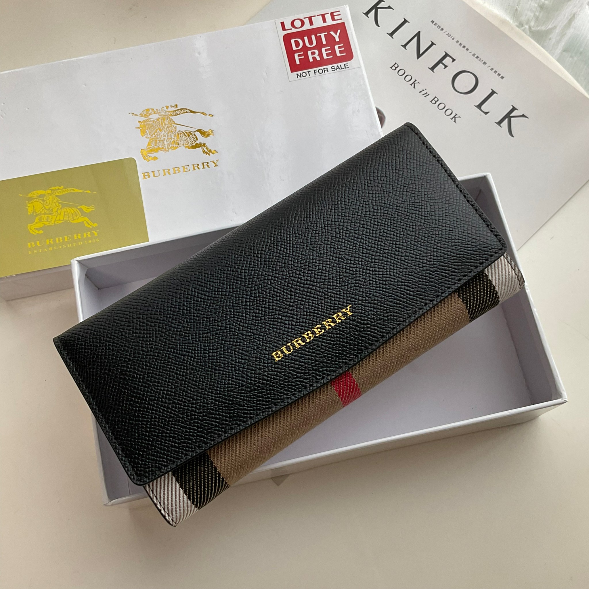 กระเป๋าสตางค์รับทรัพย์ ทรงหรู จากงาพรีเมี่ยมกิ๊ฟ Limited Edition จาก BURBERRY กระเป๋าสตางค์ใบยาวแบบพับกระดุม ทูโทนด้วยหนังแท้คาดผ้าลาย vintage ด้านในมีช่องใส่ธนบัตรยาวทั้งสองฝั่ง ช่องใส่บัตรได้อย่างน้อย 12 ช่อง และช่องเปิดด้วยซิปปั้มแบรนด์อะไหล่ทองสุดหรู 