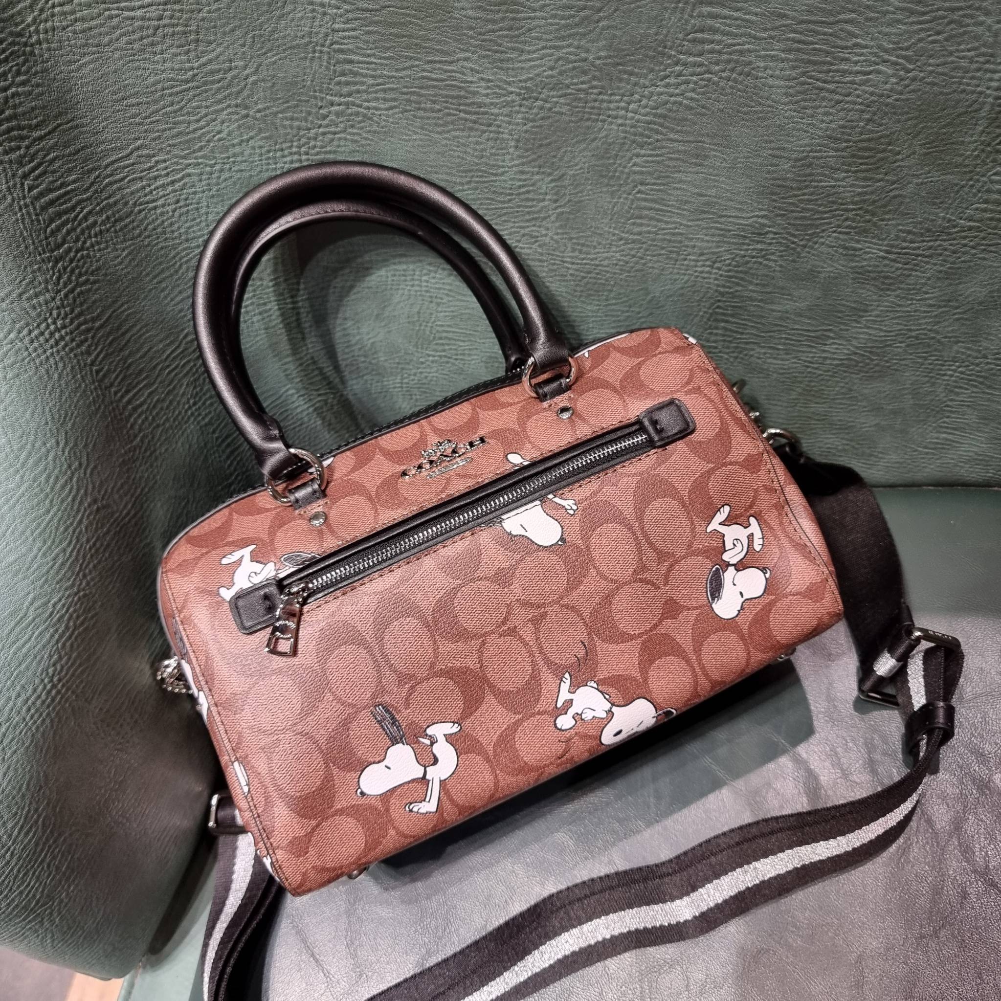 COACH C4118 COACH x PEANUTS ROWAN SATCHEL IN SIGNATURE CANVAS WITH SNOPPY PRINT สนูปพีที่สุดของคอลเลคชั่นแห่งความน่ารัก มาในดีไซน์ของกระเป๋าทรงหมอนยอดฮิต คลาสสิคใช้งานได้ไม่มีเบื่อ รอบนี้มาให้พร้อมสายสะพาย crossbody แบบสปอร์ต ทำให้ใช้งานได้อย่างกระฉับกระเ