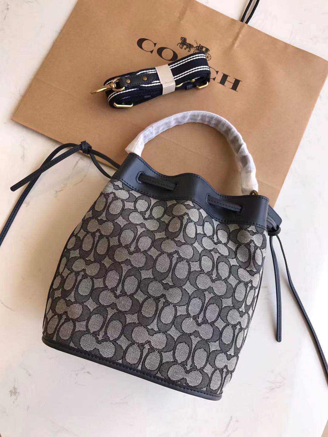 COACH FIELD BUCKET BAG IN SIGNATURE JACQUARD C3853 กระเป๋าสะพายทรงบัคเก็ต รุ่นใหม่ล่าสุด ดีไซน์ลายซิกเนเจอร์บนผ้า jacquard สวยคม เป็นเอกลักษณ์ไม่ซ้ำใคร มาพร้อมสายสะพายผ้าสปอร์ต และสายสั้นสำหรับคล้องแขนได้ สามารถรูดปิดปากกระเป๋าด้วยหนังรอบใบ เพิ่มดีเทลให้ต