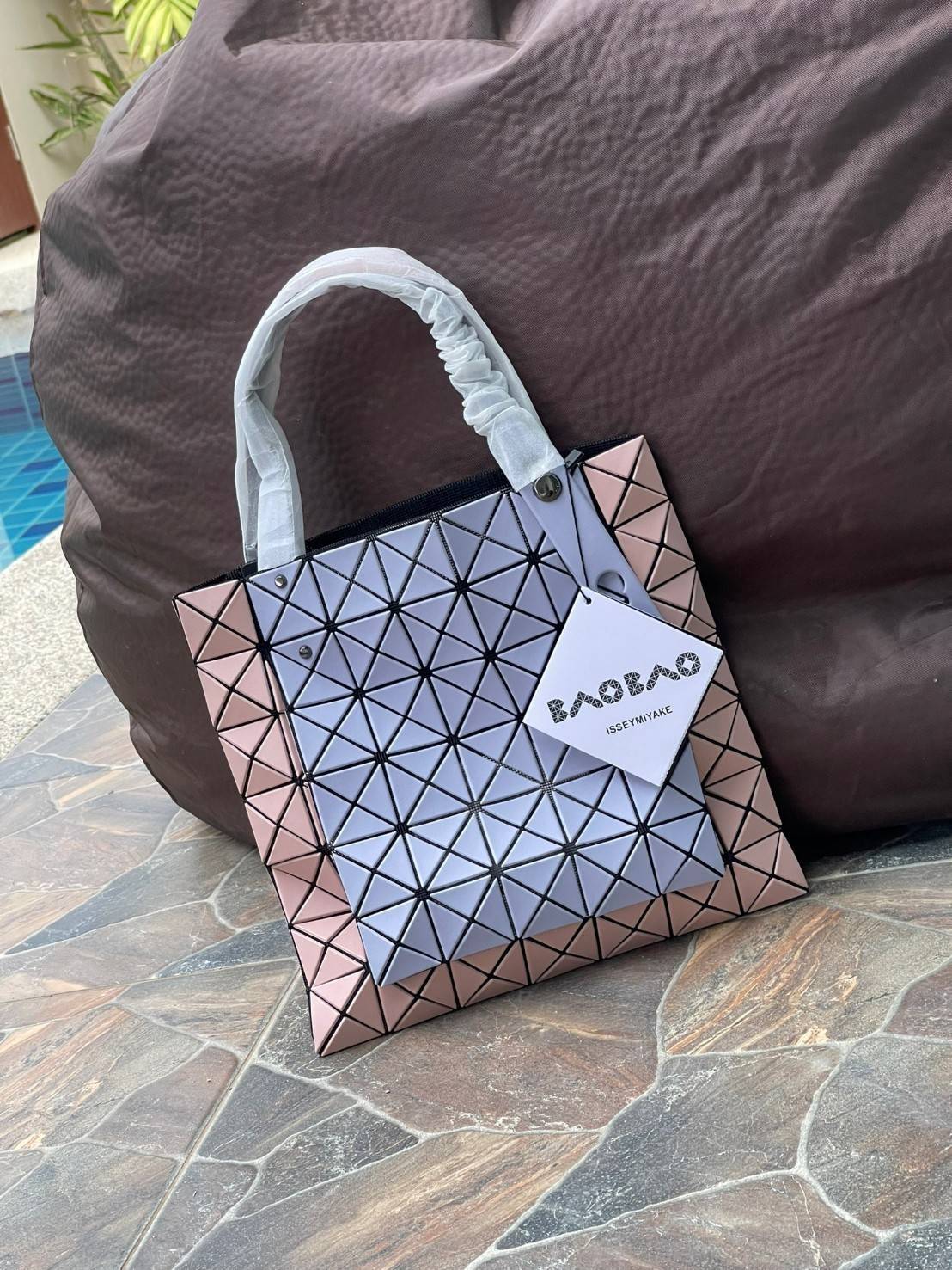 Baobao Issey Miyake Prism Kangaroo tote bag กระเป๋าถือทรงโท้ทที่ประดิษฐ์ขึ้นอย่างเชี่ยวชาญในญี่ปุ่น มาพร้อมแผงเรขาคณิตสำหรับการออกแบบที่ได้รับแรงบันดาลใจจากกระดาษพับ ซิลลูเอทอันเป็นเอกลักษณ์นี้ปิดท้ายด้วยสายรัดแบบอสมมาตร มีการพัฒนาโครงสร้างทรงสามเหลี่ยมเพ