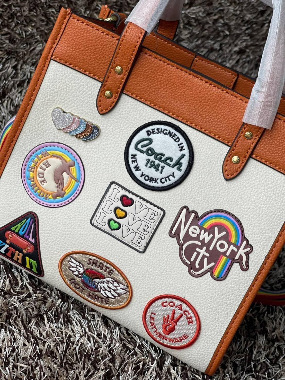 COACH FIELD TOTE 22 WITH PATCHES CA138 ส่วนหนึ่งจาก Coach Pride Collection ซึ่งเป็นการเฉลิมฉลองความเท่าเทียม ความหลากหลาย และการแสดงออกถึงตัวตนที่แท้จริงภายในชุมชน LGBTQIA+ ในเดือนนี้และทุกเดือน ตั้งแต่วันธรรมดาที่วุ่นวายไปจนถึงวันหยุดสุดสัปดาห์ที่เต็มไปด