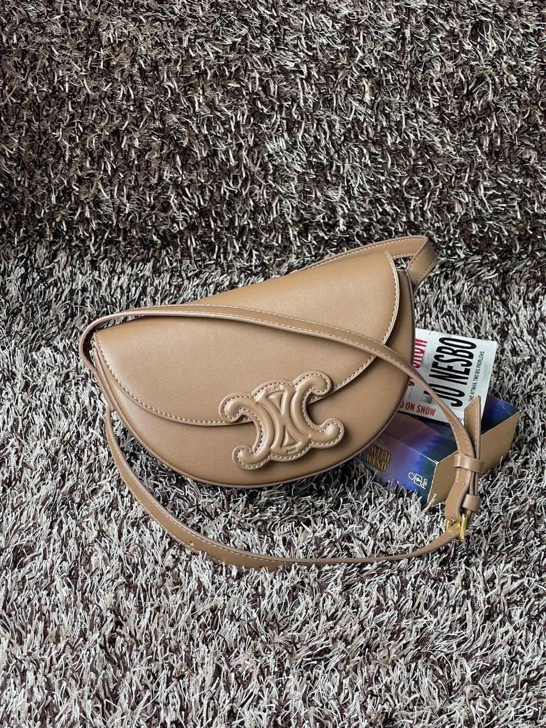 CELINE BESACE CUIR TRIOMPHE IN SMOOTH กระเป๋ารุ่นนี้นำเสนอในรูปทรงฮาล์ฟมูนที่ตอนนี้กำลังงมาแรง เปิดด้วยกระดุมแป๊กเพื่อเผยให้เห็นช่องภายในที่กว้างขวางและกระเป๋าด้านในแบบแบน คุณสมบัติที่โดดเด่นอีกอย่างของกระเป๋าอยู่ที่โลโก้ขนาดใหญ่ รูปทรงสะดุดตา สามารถสะพาย