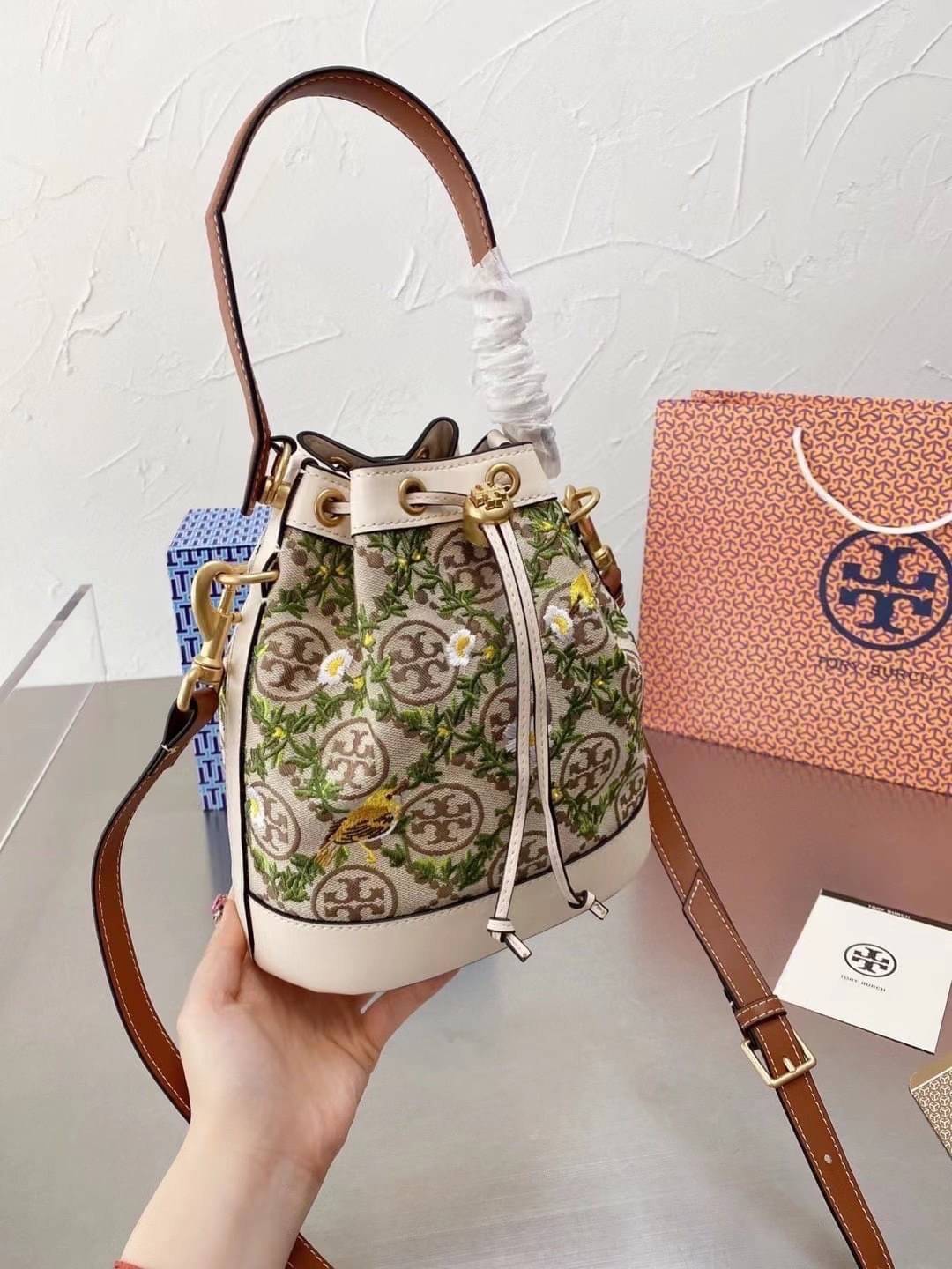 TORY BURCH T MONOGRAM JACQUARD EMBROIDERED BUCKET BAG ครั้งแรกกับโมโนแกรม ที่ได้รับแรงบันดาลใจมาจากโลโก้สุดคลาสสิก กลับมาอีกครั้งในรูปแบบของ ลวดลาย T Monogram ที่ผสมผสานความร่วมสมัยเข้ากับความเป็นเอกลักษณ์ของแบรนด์เข้าไว้ด้วยกัน โดยเป็นการนำเอาลวดลาย T Mo
