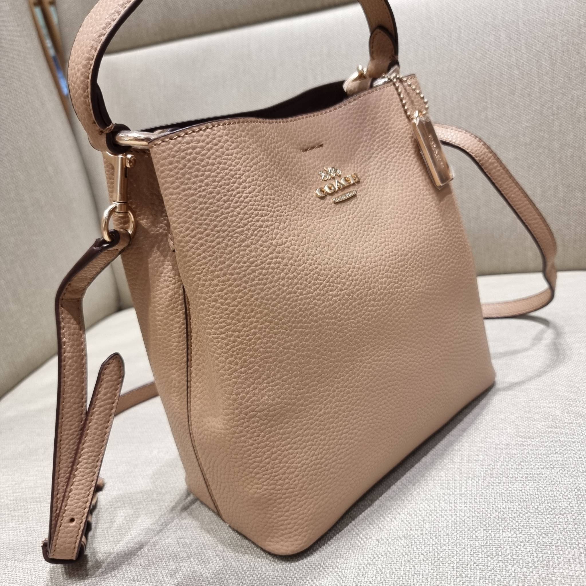 COACH 1011 SMALL TOWN BUCKET BAG รุ่นยอดนิยมใบเล็ก กระเป๋าทรงบัคเก็ต สีคลาสสิคเรียบหรู ตัดกับโลโก้สีทองดูโดดเด่น วัสดุหนัง pepble สวยคมทุกมุมจริงๆ!! เปิด-ปิดด้วยกระดุมแม่เหล็กทั้ง 2 ฝั่ง ภายในเป็นช่องโล่ง มาพร้อมสายสะพายปรับได้ตามตัว ขนาดใบนี้กำลังสวย สะพ