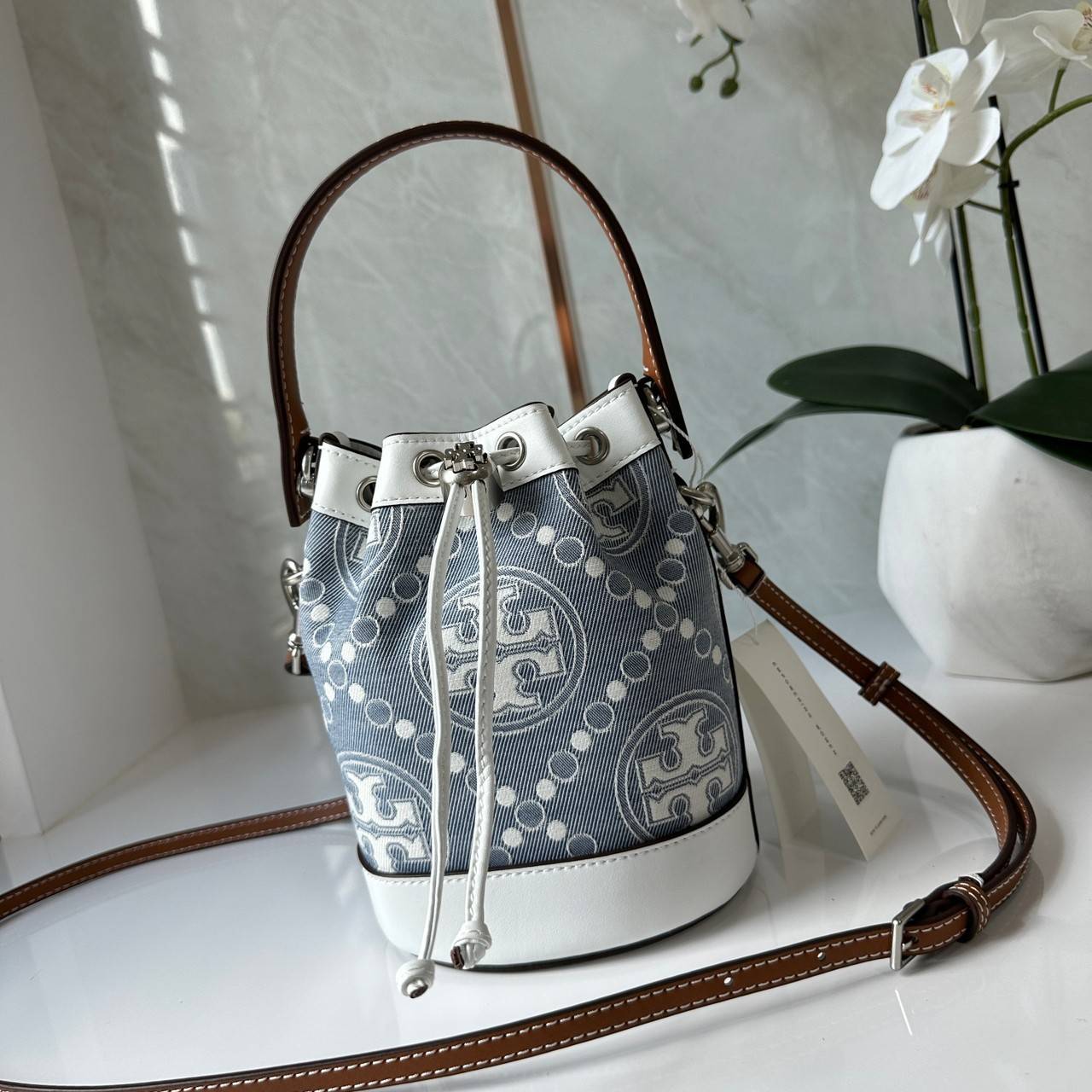 TORY BURCH Mini T Monogram Denim Bucket Bag คอลเลคชั่นใหม่ รูปแบบคลาสสิค พกพาความหรูหราไปได้ทุกที่ด้วยกระเป๋าทรง Bucket ขนาดกลางและปิดด้วยเชือกรูดพร้อมโลโก้แวววาว วัสดุผ้าเดนิมแจ็คการ์ด ตัดขอบหนังแท้ สวยหรู ทันสมัยสุดๆคะ