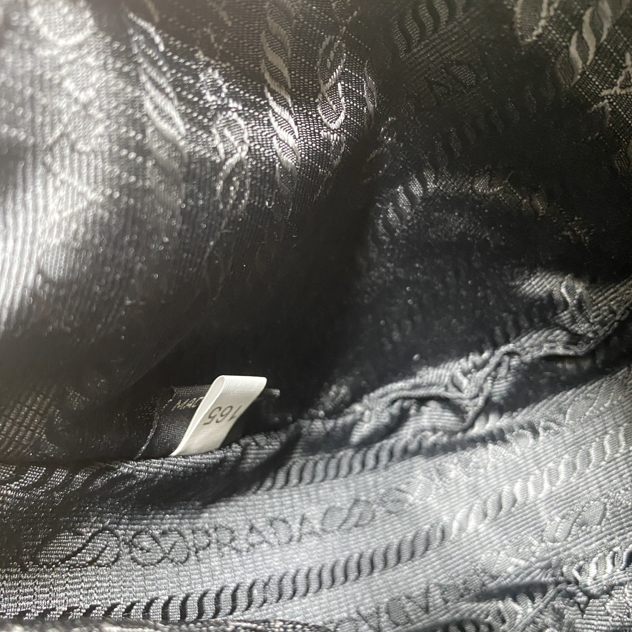 ORI หนังแท้ | Prada Re-Edition 2005 bag in Naplak leather กระเป๋าสะพายทรงโฮโบหนังแก้ว ดีไซน์เอฟเฟกต์มันวาวและเท็กซ์เจอร์ที่มีเสน่ห์สไตล์วินเทจ พร้อมทริกห้อยเพิ่มสไตล์สัมผัสที่โดดเด่นและร่วมสมัยยิ่งขึ้น