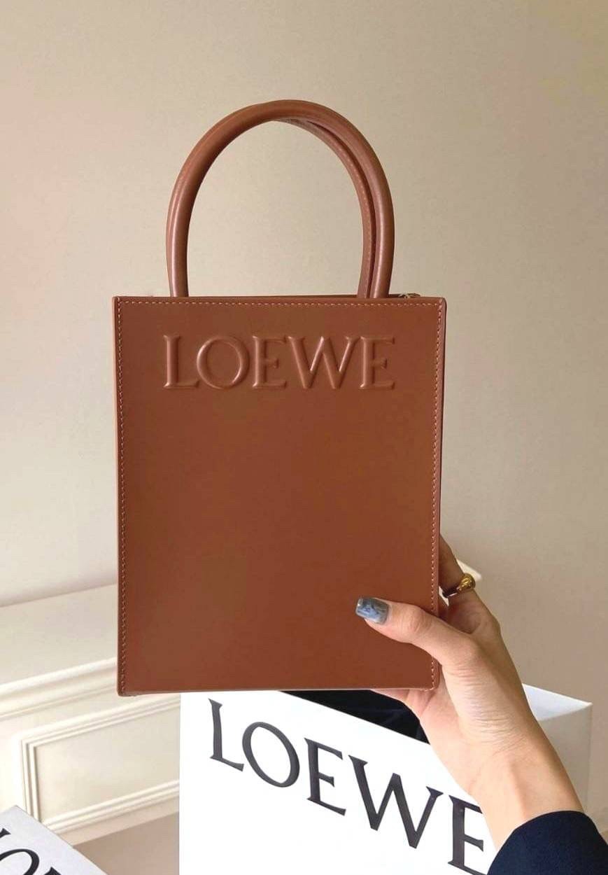 LOEWE Tote Leather Bag พร้อมส่ง กระเป๋าทรงโท้ทหนังเรียบสวยอยู่ทรงด้านหน้ามีโลโก้แบรนด์ หูจับแข็งแรงมาพร้อมสายสะพายหนังเรียบยาวปรับระดับได้จะถือหรือสะพายไหล่สะพายเฉียงก็ดูดี