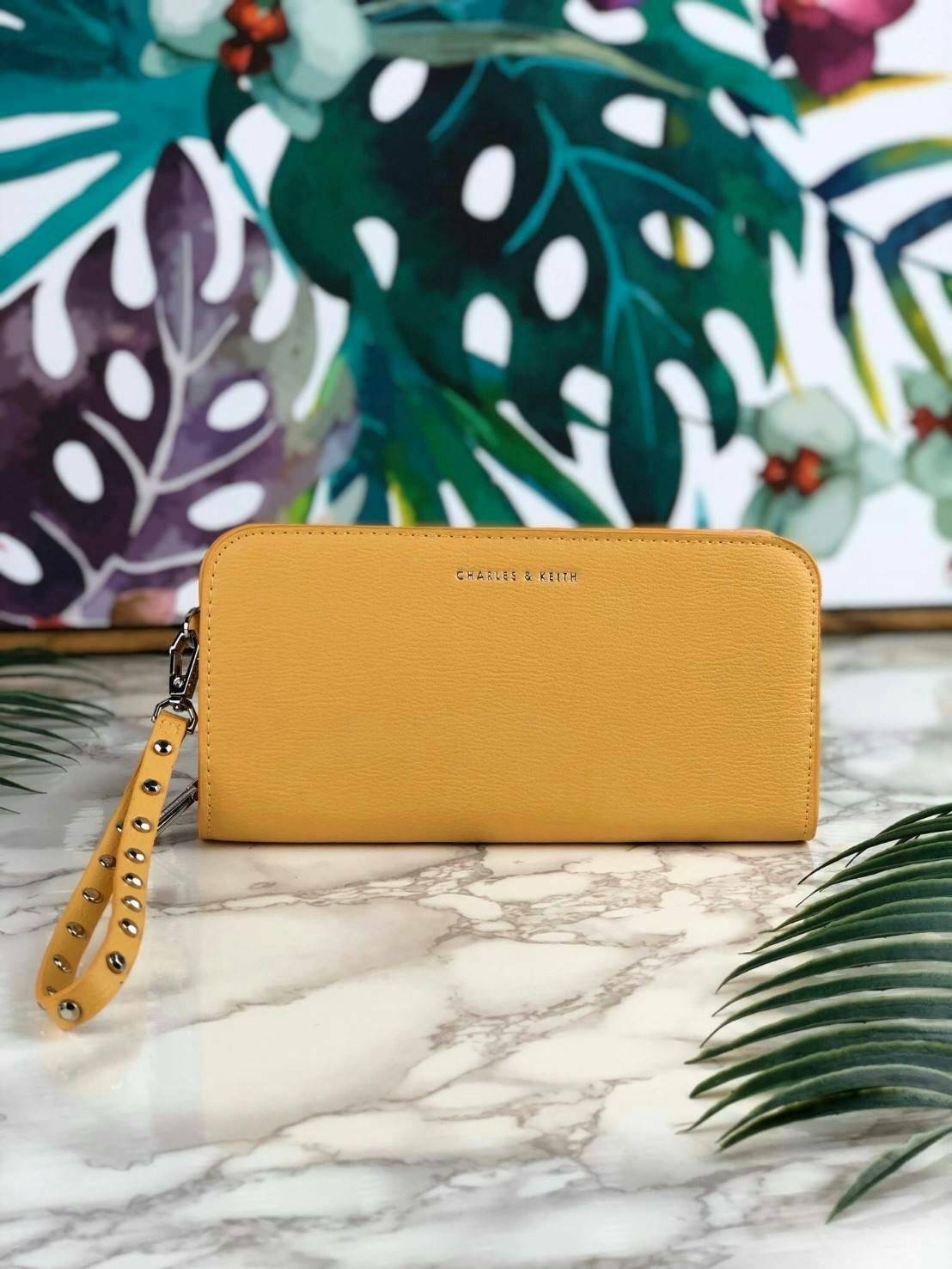 CHARLES & KEITH CLASSIC ZIP AROUND WALLET กระเป๋าเงินใบยาวซิปรอบ มีสายคล้องมีสีเข้ากระเป๋า 1 เส้น ใช้งานง่ายมากๆ คล้องมือก็เก๋ ด้านหน้าปั๊มโลโก้แบรนด์ เปิดปิดด้วยซิปรอบ ที่สายคล้องมือแต่งหมุดสีสวยเด่น ถอดสายได้ จุบัตรได้ 12 ใบ มีช่องซิปใส่เหรียญและช่องใส่