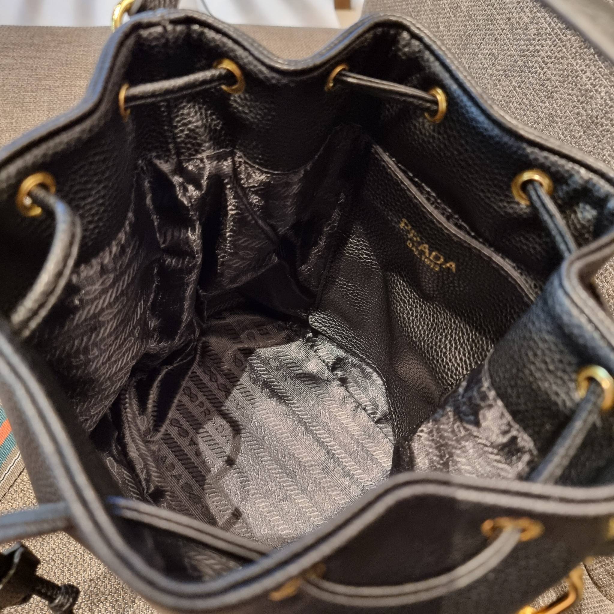 Prada leather bucket bag กระเป๋าสะพายทรงขนมจีบ ดีไซน์เรียบ แต่หรู น่าใช้มากๆ หนังสวยมาก วัสดุหนัง pepble สัมผัสนิ่มมือ ตกแต่งโลโก้สีทองตัดหนังดำ คือเลิศ!! ปากกระเป๋ารูดเปิดปิดได้ สะดวกใช้งาน ภายในโล่งกว้าง จุของได้เยอะ ไม่ธรรมดาเลย พิเศษ!! นอกจากสายคล้องใ