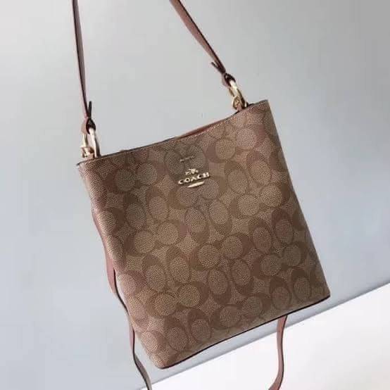COACH SMALL TOWN BUCKET BAG IN SIGNATURE สำหรับสาวแฟชั่นที่ชอบรายละเอียดชิคๆ ดีไซน์สุดเก๋ แนะนำเลยสำหรับกระเป๋าทรงบักเก็ตใบนี้ เชื่อว่าสาว ๆ หลายคนชื่นชอบ เป็นไอเทมที่สามารถแมทช์ได้กับเสื้อหลากหลายสไตล์ บรรจุของได้เยอะโดยที่กระเป๋าไม่เสียทรง แบ่งช่องใช้งา