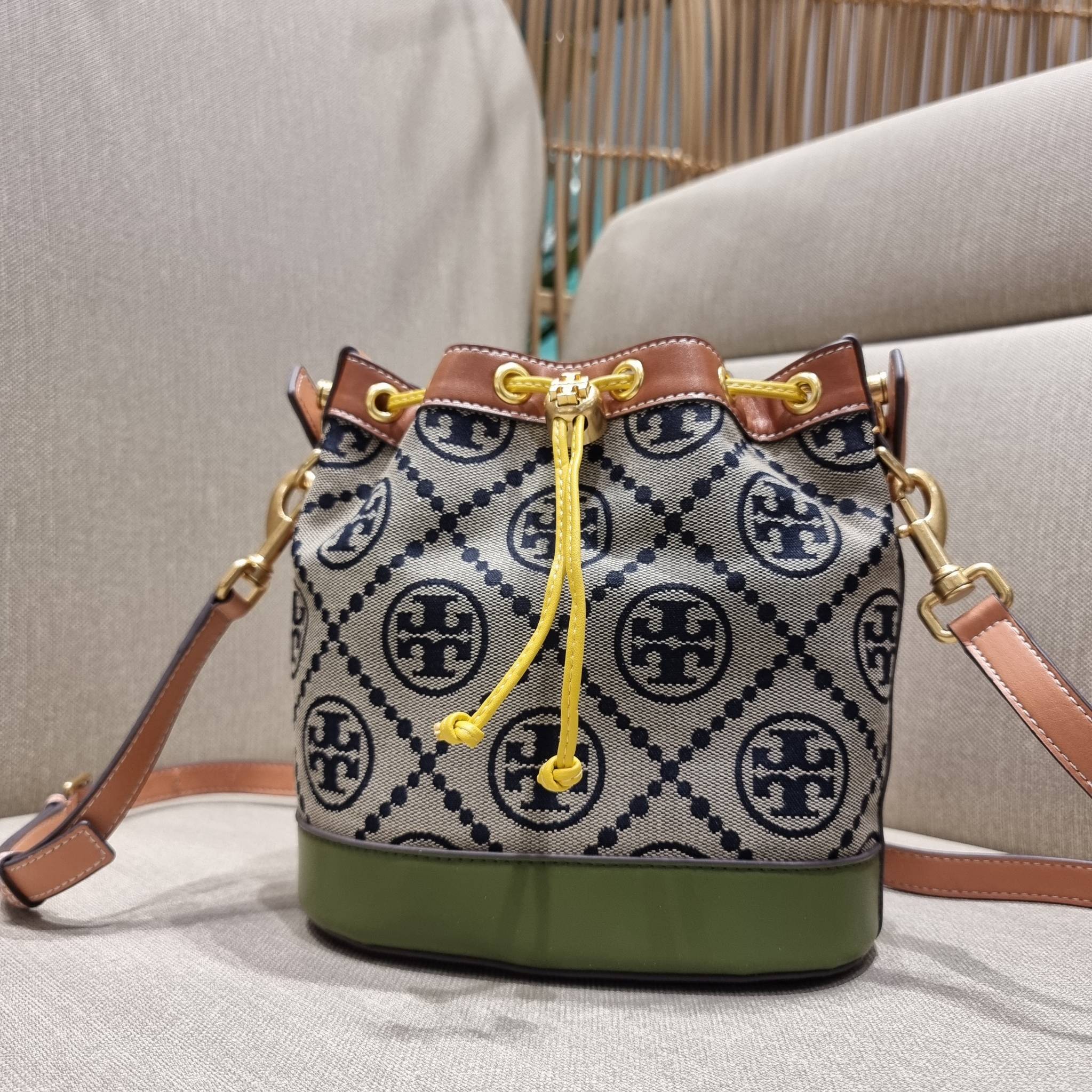 TORY BURCH T MONOGRAM COLORBLOCK JACQUARD BUCKET BAG ไอเท็มใหม่ที่ใครๆก็รอ กระเป๋าบัคเก็ตทรงสวย ที่ยังคงให้ความโดดเด่นด้วยลวดลายเอกลักษณ์ เพิ่มเติมดีไซน์บล็อคสี ตัดกันได้อย่างลงตัว ถักทอบนวัสดุ woven jacquard ลายคมชัด สลับส่วนของหนังแท้ ภายในเป็นช่องโล่งก