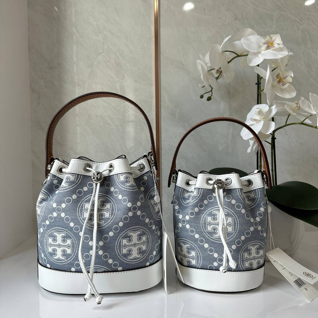 TORY BURCH Mini T Monogram Denim Bucket Bag คอลเลคชั่นใหม่ รูปแบบคลาสสิค พกพาความหรูหราไปได้ทุกที่ด้วยกระเป๋าทรง Bucket ขนาดกลางและปิดด้วยเชือกรูดพร้อมโลโก้แวววาว วัสดุผ้าเดนิมแจ็คการ์ด ตัดขอบหนังแท้ สวยหรู ทันสมัยสุดๆคะ