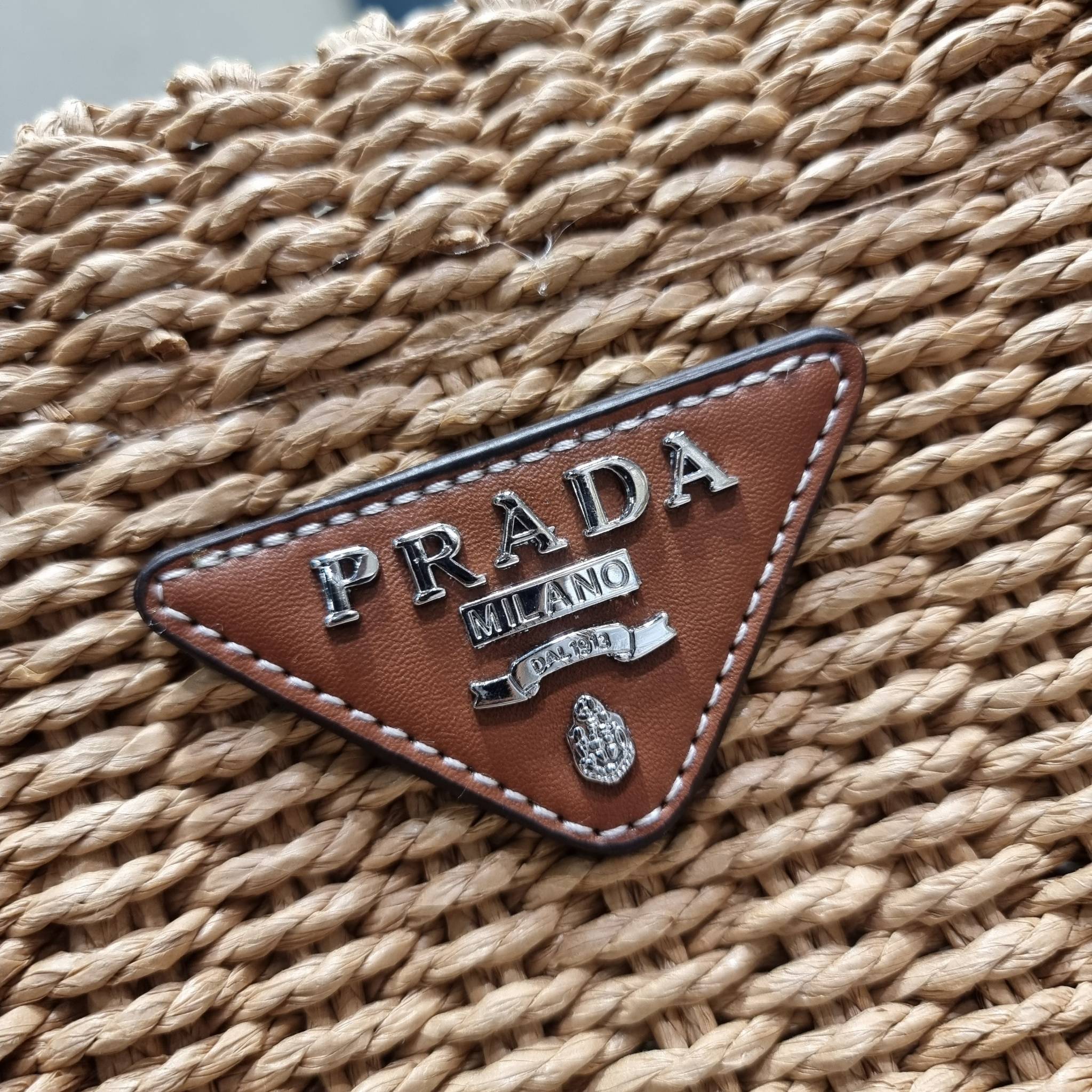 PRADA CORN HUSK AND LEATHER TOTE ธรรมชาติเป็นหนึ่ง!! กับอีกไอเท็มรักษ์โลก ด้วยดีไซน์ล้ำทันสมัย ผสานกับวัสดุจากธรรมชาติ ออกมาเป็นลายสานที่สวยหรู ไม่กระด้าง กระเป๋าทรงโท้ท ขนาดกำลังสวย มาพร้อมหูจับในตัว มีซิปรูปเปิด-ปิดที่ปากกระเป๋า ภายในโล่งกว้าง ใส่ของได้