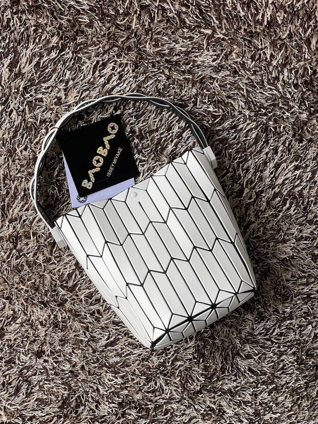 Small : BAO BAO ISSEY MIYAKE SMALL BUCKET เป็นกระเป๋าบัคเก็ตขนาดเล็กสามารถใช้ใส่กระเป๋าสตางค์และโทรศัพท์มือถือได้ ซีรีย์ใหม่นี้มีจุดเด่นที่แผ่นรูปทรงสี่เหลี่ยมด้านขนานในแนวตั้ง เกิดเป็นรูปทรงสามมิติซึ่งแตกต่างไปจากรูปทรงที่เกิดขึ้นจากแผ่นสามเหลี่ยม หูหิ้ว