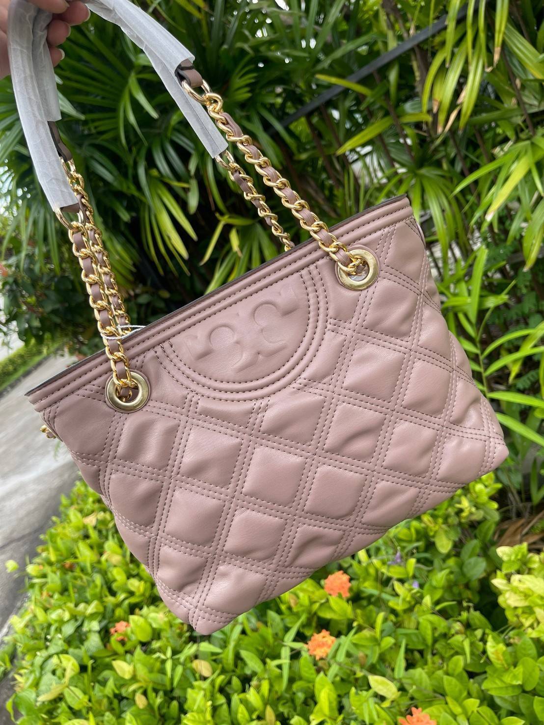 Tory Burch Fleming Soft Small Tote Bag เป็นกระเป๋าสะพายไหล่น่ารัก ๆ สักใบที่มีดีไซน์โดดเด่น สะดุดตา ใน Collection เรียกได้ว่าขายดีอันดับต้น ๆ ของแบรนด์ ใช้ได้ในลุคช์ทางการและกึ่งทางการ ดีเทลการตัดเย็บพิมพ์ลายนูนคู่กับแพทเทิร์นสี่เหลี่ยมทรงเพชร ที่ช่วยเพิ่