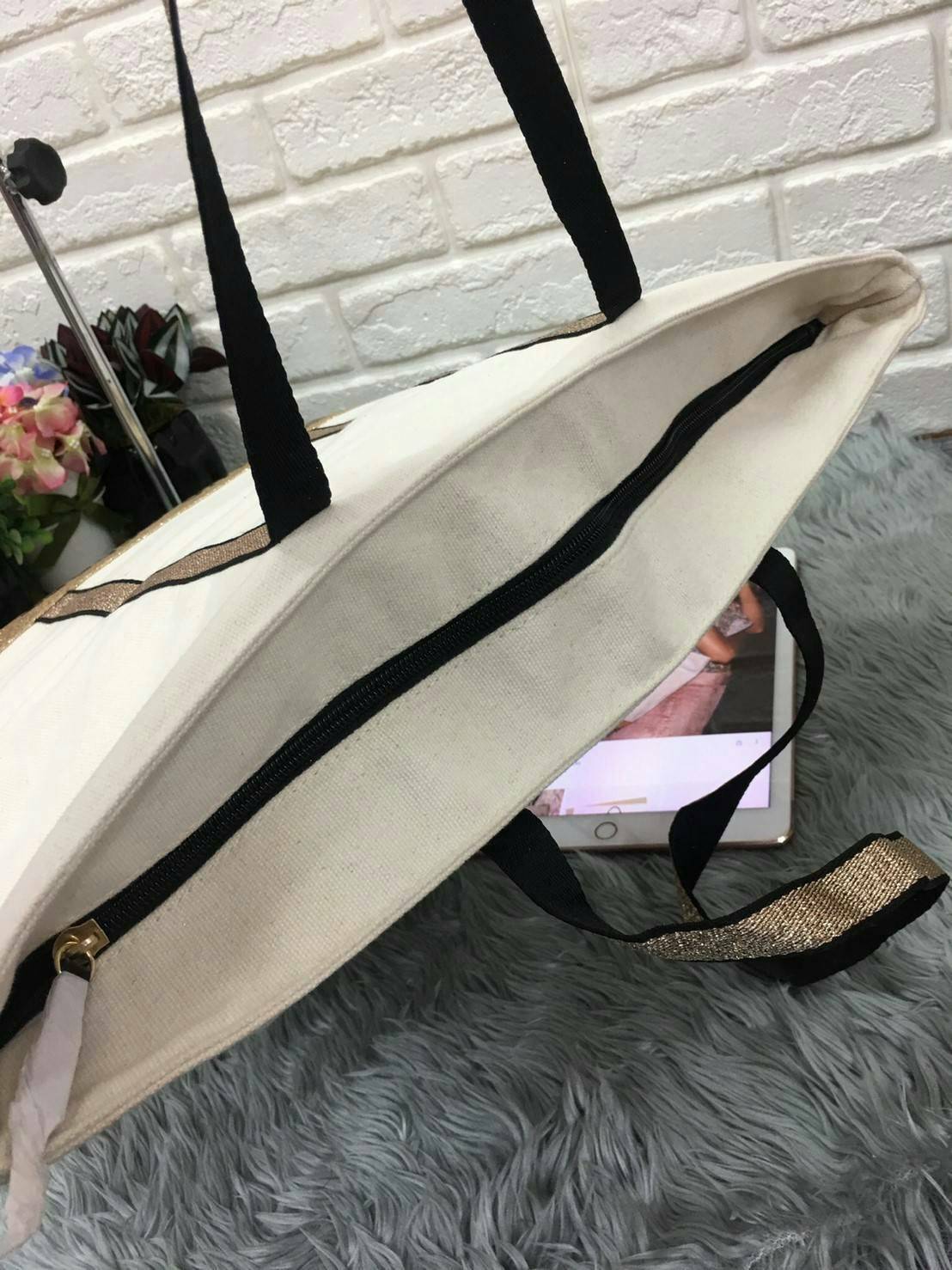 Victoria's Secret Canvas Tote Bag กระเป๋าสะพายวัสดุแคสวาสสีครีม ด้านล่างเป็นกลิตเตอร์ สกรีนชื่อแบรนด์ ฐานกระเป๋าเป็นหนัง ด้านหน้ามีช่องเล็กไว้ใส่ของได้ เปิดปิดด้วยซิป ซับในลายแบรนด์ มีช่องซิปเล็กแยกใส่ของ1ช่อง จุของได้เยอะมาก