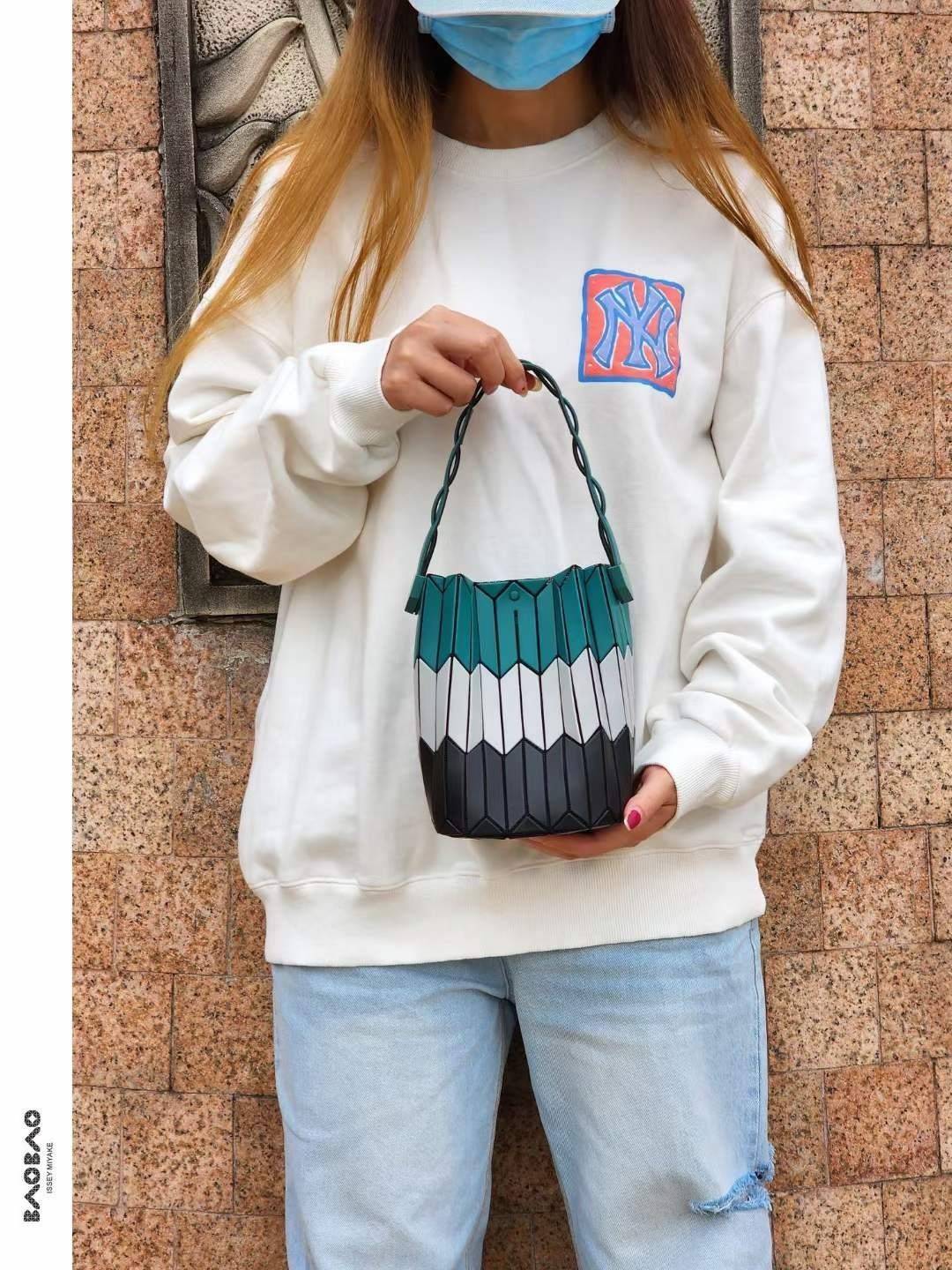 Small : BAO BAO ISSEY MIYAKE SMALL BUCKET เป็นกระเป๋าบัคเก็ตขนาดเล็กสามารถใช้ใส่กระเป๋าสตางค์และโทรศัพท์มือถือได้ ซีรีย์ใหม่นี้มีจุดเด่นที่แผ่นรูปทรงสี่เหลี่ยมด้านขนานในแนวตั้ง เกิดเป็นรูปทรงสามมิติซึ่งแตกต่างไปจากรูปทรงที่เกิดขึ้นจากแผ่นสามเหลี่ยม หูหิ้ว