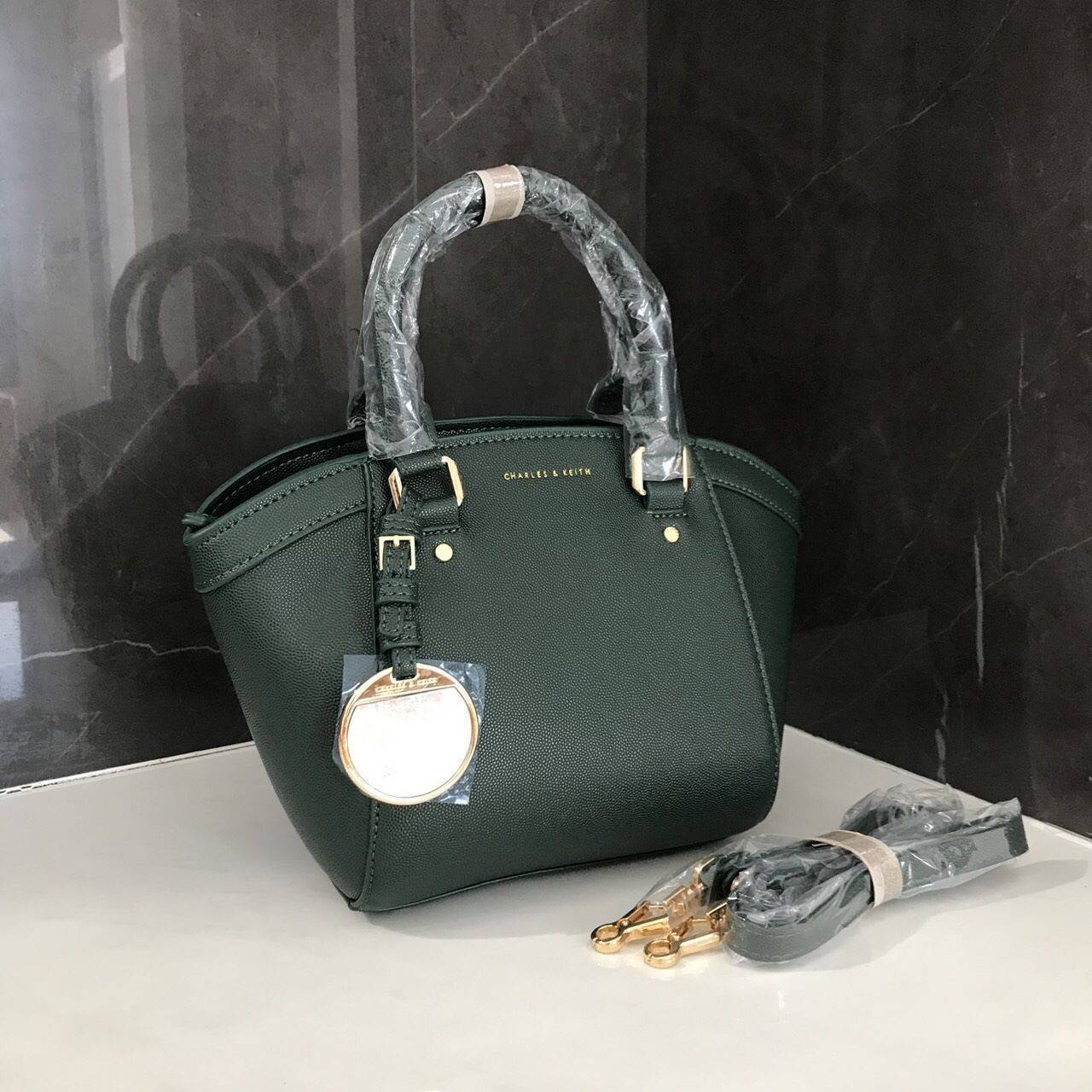 CHARLES & KEITH CITY BAG กระเป๋าถือหรือสะพาย ตั้งอยู่ทรงสวย มีโลหะรองฐาน เปิดปิดด้วยซิปเดียว ภายในมี 2 ช่องเล็กด้านหน้าประดับด้วยกระจกทรงกลม ใช้งานได้จริง ปั้มโลโก้แบรนด์ มาพร้อมสายสะพายยาว ปรับระดับและถอดสายได้ หูพับลงได้ น้ำหนักเบา ต้องมีไว้ครอบครองสักใ