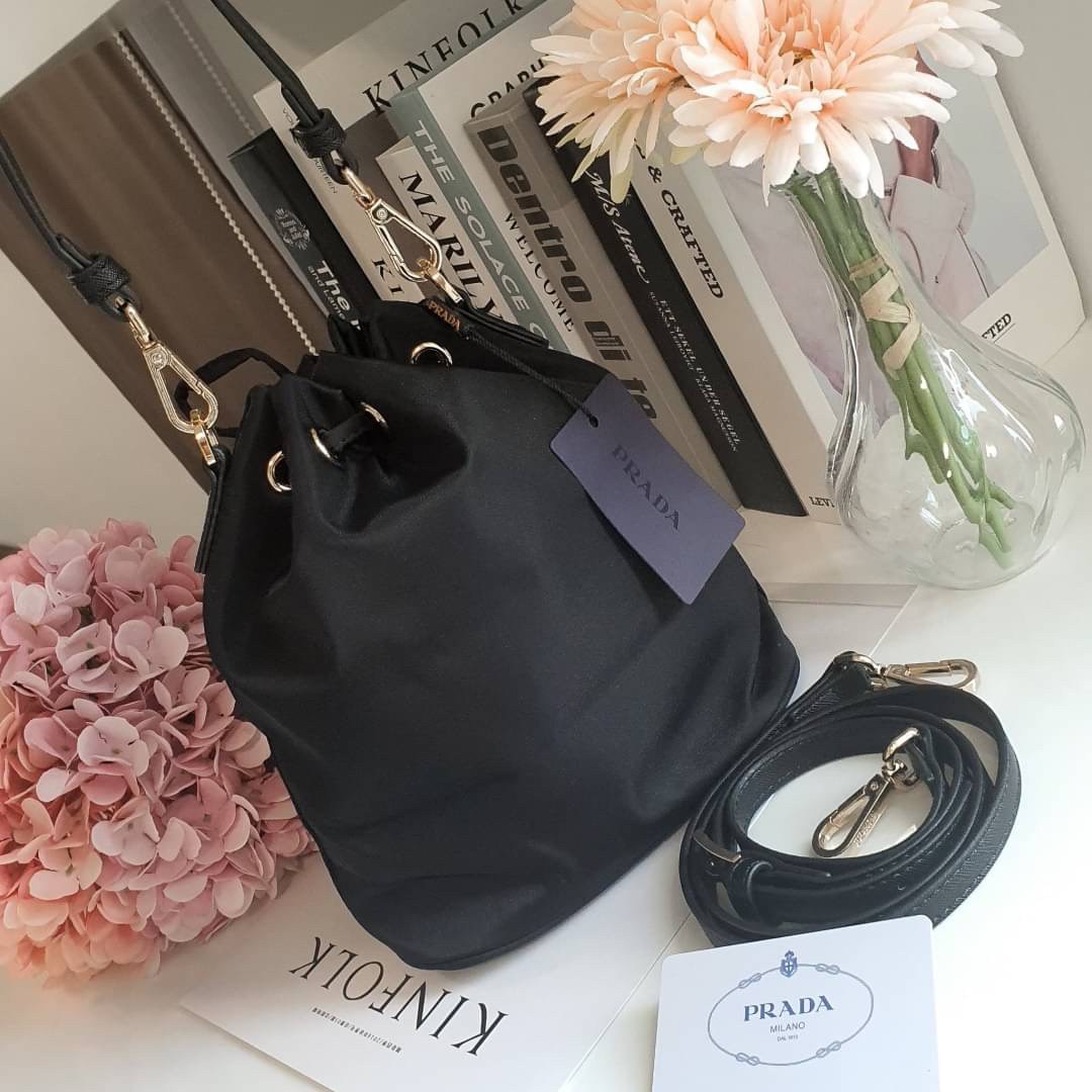 Size MINI : พร้อมส่งรุ่นขายดี!!! PRADA DRAWSTRING BAG WITH STRAP VIP GIFT WITH PURCHASE พรีเมี่ยมกิ๊ฟจากต่างประเทศรุ่น Limited วัสดุ Nylon & Polyester 100% เนื้อหนา ด้านหน้าประดับโลโก้ เปิดปิดแบบ Drawstring มาพร้อมสายสะพายให้ถึง2แบบทั้งสายสั้นและสายยาวปรั