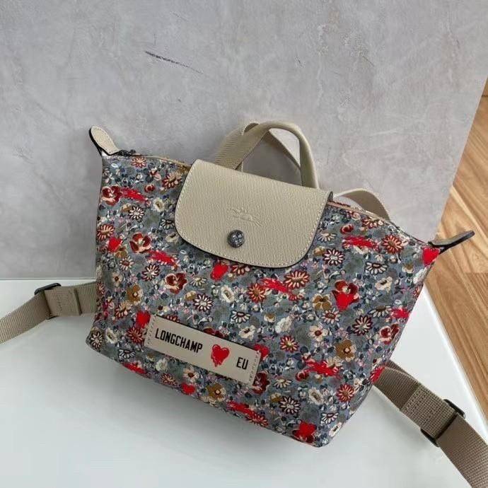 Longchamp X Eu Backpack กระเป๋าเป้สะพายหลังลายดอกๆไม้ วัสดุผ้าฝ้าย อะไหล่สีดำ กระเป๋าเป้แบบลำลองสำหรับสตรีซึ่งนำรูปทรงอันเป็นเอกลักษณ์ของ Le Pliage มาปรับใช้กับทุกสถานการณ์ อุปกรณ์เสริมที่ใช้งานได้จริงนี้มีสายรัดปรับระดับได้และที่จับช่วยให้ สะพายข้างหรือส
