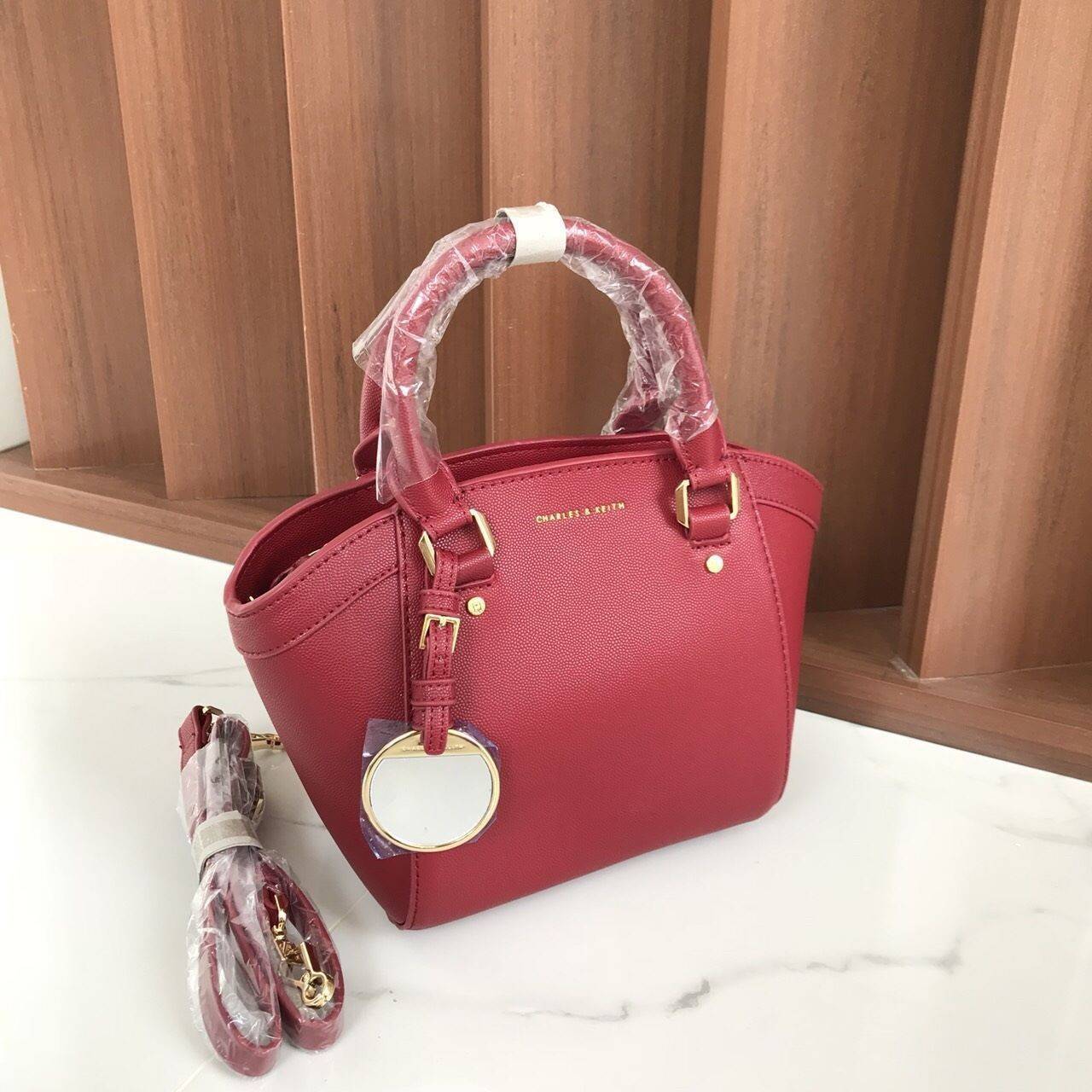 CHARLES & KEITH CITY BAG กระเป๋าถือหรือสะพาย ตั้งอยู่ทรงสวย มีโลหะรองฐาน เปิดปิดด้วยซิปเดียว ภายในมี 2 ช่องเล็กด้านหน้าประดับด้วยกระจกทรงกลม ใช้งานได้จริง ปั้มโลโก้แบรนด์ มาพร้อมสายสะพายยาว ปรับระดับและถอดสายได้ หูพับลงได้ น้ำหนักเบา ต้องมีไว้ครอบครองสักใ