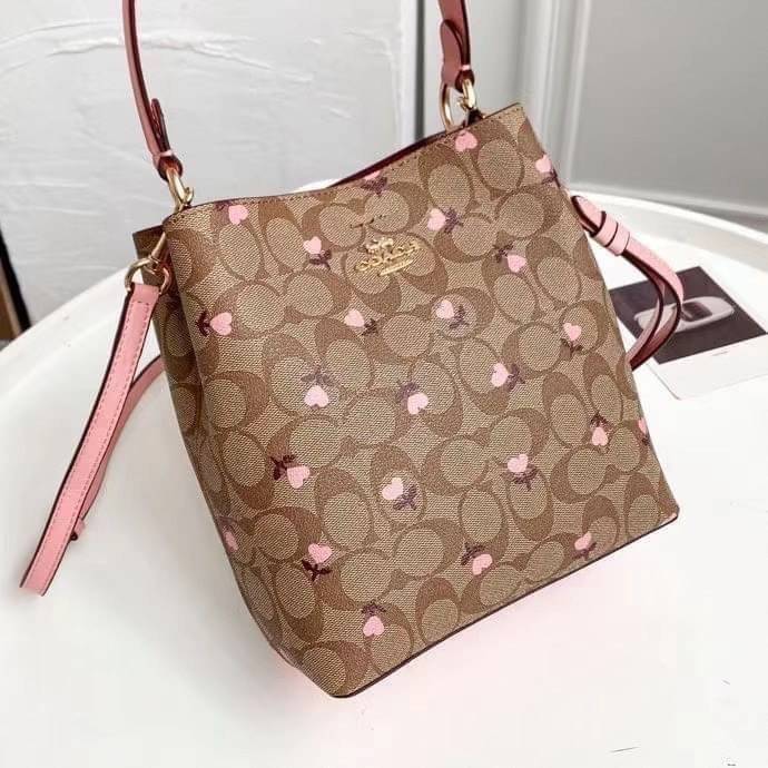 OUTTLET 】COACH SMALL TOWN BUCKET BAG IN SIGNATURE WITH Heart floral print สำหรับสาวแฟชั่นที่ชอบรายละเอียดชิคๆ ดีไซน์สุดเก๋ แนะนำเลยสำหรับกระเป๋าทรงบักเก็ตใบนี้ เชื่อว่าสาว ๆ หลายคนชื่นชอบ เป็นไอเทมที่สามารถแมทช์ได้กับเสื้อหลากหลายสไตล์ บรรจุของได้เยอะโดยท