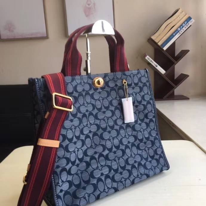 COACH Tote 34 In Signature Chambray หากคุณกำลังมองหากระเป๋าที่มีดีไซน์แปลกตา ไม่ค่อยเหมือนที่พบเห็นทั่วไป ต้องเป็นรุ่นนี้เลยค่ะ นอกจากจะผลิตจากผ้าแชมเบรย์ซึ่งมีน้ำหนักเบาแล้ว ยังให้สีสันคล้ายกับสียีนส์ สายสะพายและหูหิ้วสไตล์สปอร์ต ที่สำคัญยังมีหมุดปิดกระเ