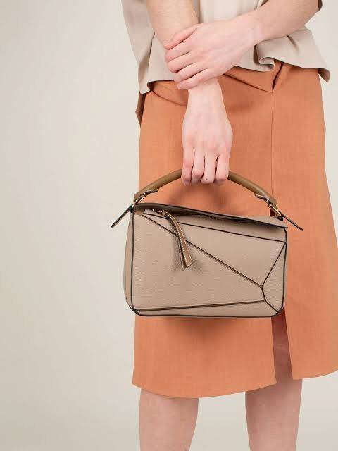 Loewe Puzzle Bag In Classic กระเป๋าทรง Puzzle นี้ออกแบบโดย Jonathan Anderson โดยได้รับแรงบันดาลใจในการออกแบบมาจากรูปทรงของลูกรักบี้ ดังนั้น จึงจะเห็นได้ว่าการตัดเย็บและรูปทรงของกระเป๋านั้นคล้ายคลึงกับลูกรักบี้ รูปทรงดูมินิมอลไม่ทิ้งคอนเซ็ปต์ของแบรนด์ สามา