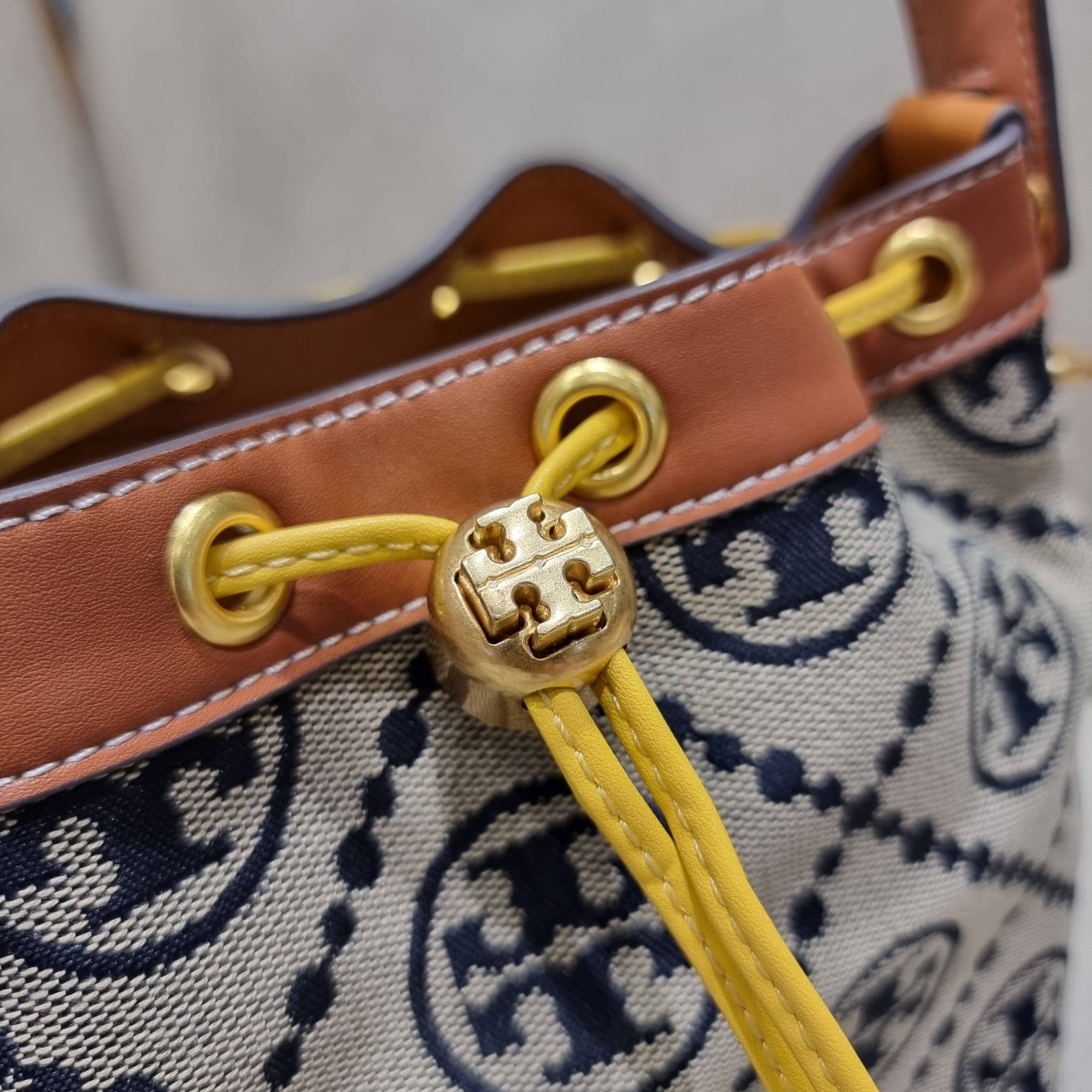 TORY BURCH T MONOGRAM COLORBLOCK JACQUARD BUCKET BAG ไอเท็มใหม่ที่ใครๆก็รอ กระเป๋าบัคเก็ตทรงสวย ที่ยังคงให้ความโดดเด่นด้วยลวดลายเอกลักษณ์ เพิ่มเติมดีไซน์บล็อคสี ตัดกันได้อย่างลงตัว ถักทอบนวัสดุ woven jacquard ลายคมชัด สลับส่วนของหนังแท้ ภายในเป็นช่องโล่งก