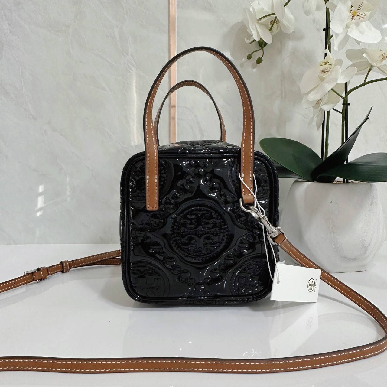 Tory Burch T Monogram Embroidered Patent Cube คอลเลคชั่นใหม่ รุ่นลิมิเต็ดรูปทรงใหม่ T Monogram สุดcube วัสดุหนังแท้ เปิด-ปิดด้วยซิป ภายในกว้าง มีช่องแยก 1 ช่อง สามารถใส่โทรศัพท์มือถือได้ทุกรุ่น สามารถถือหิ้วหรือสะพายได้ สายสามารถถอดและปรับระดับได้คะ