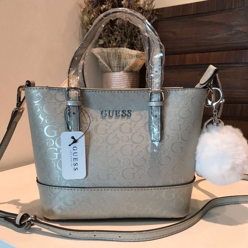 GUESS MINI CROSS BODY BAG กระเป๋าถือหรือสะพายรุ่นฮิตและขายดีที่สุดจาก GUESS FACTORY วัสดุหนังแก้วเงาสวยอยู่ทรง น้ำหนักเบา ด้านหน้าประดับด้วยโลโก้แบรนด์สุดหรูพร้อมปอมๆห้อยที่หูกระเป๋าถอดเเยกใช้ได้ เปิดปิดกระเป๋าด้วยซิปสะดวกใช้ ด้านในโล่งกว้างมีช่องซิปและช่