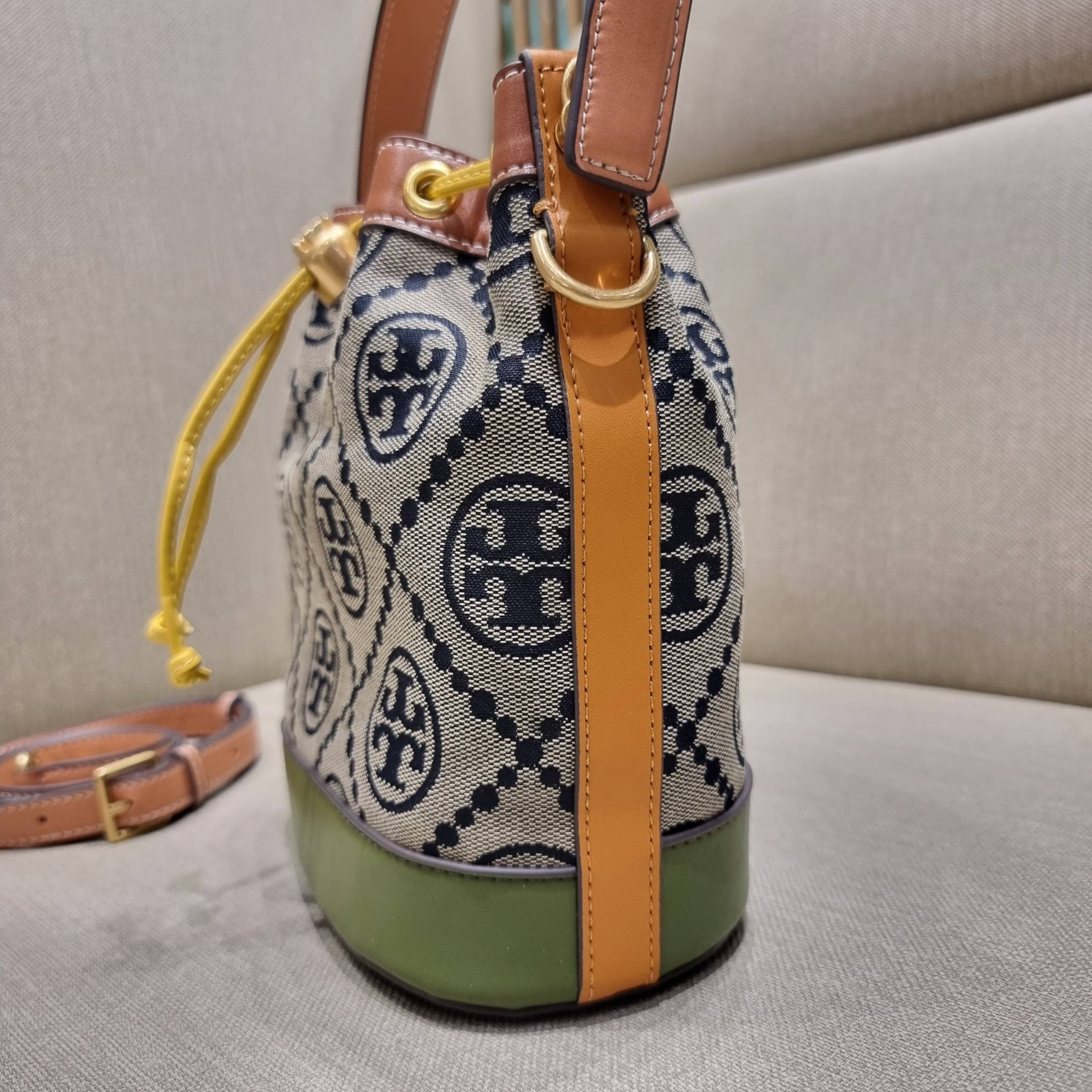 TORY BURCH T MONOGRAM COLORBLOCK JACQUARD BUCKET BAG ไอเท็มใหม่ที่ใครๆก็รอ กระเป๋าบัคเก็ตทรงสวย ที่ยังคงให้ความโดดเด่นด้วยลวดลายเอกลักษณ์ เพิ่มเติมดีไซน์บล็อคสี ตัดกันได้อย่างลงตัว ถักทอบนวัสดุ woven jacquard ลายคมชัด สลับส่วนของหนังแท้ ภายในเป็นช่องโล่งก