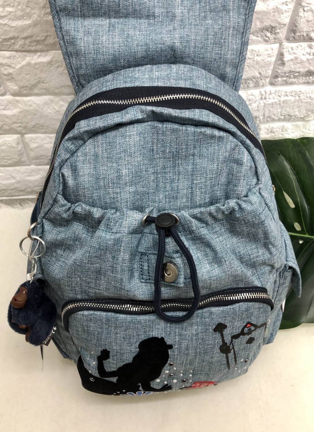 Kipling Disney's Alice in Wonderland Printed Backpack กระเป๋าเป้ Limited คอลเลคชั่น ALICE วัสดุ Denim+Polyester 100% เปิดปิดด้วยฝาปิด กระดุมแม่เหล็ก และซิปรอบ มาพร้อมพวงกุญเเจลิง ถอดเเยกใช้ได้ มีช่องซิปด้านหน้า และด้านหลัง พร้อมช่องใส่ของด้านข้าง 2 ด