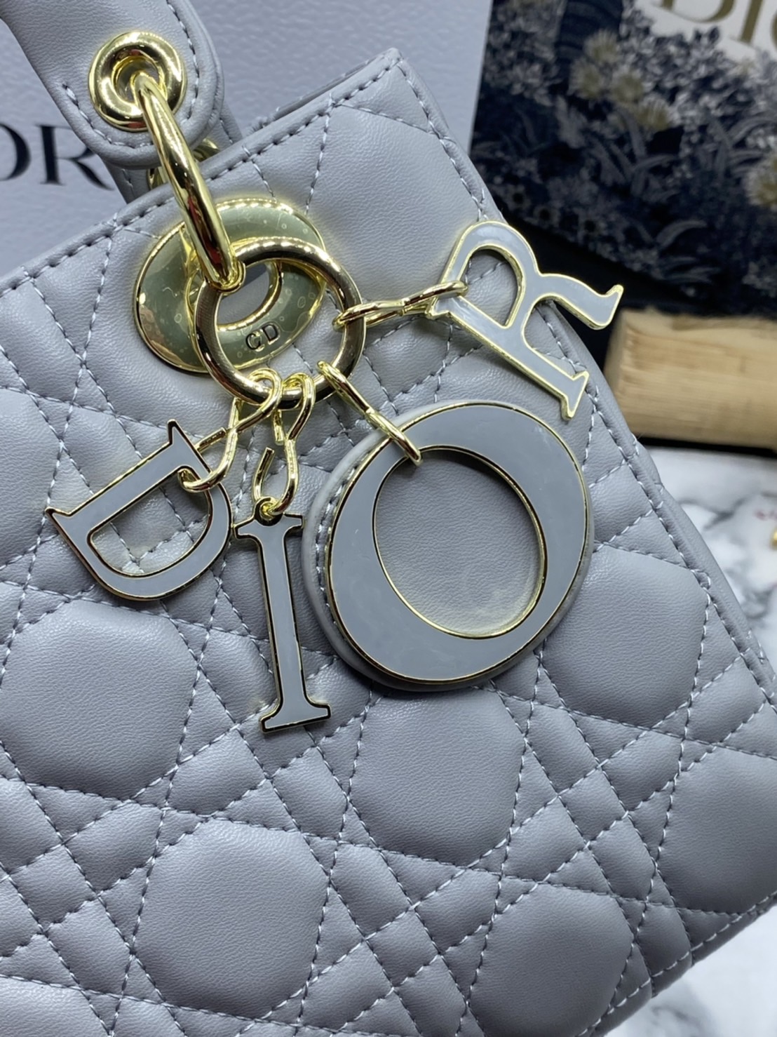 หนังแท้ DIOR LADY BAG 20cm ความสง่างามอีกหนึ่งรุ่นของ Dior รูปทรงสีเหลียม ขนาดกระทัดรัด ตั้งอยู่ทรง ฐานกระเป๋าแข็งแรง มีหมุดรองฐาน ดีไซน์ที่มีเอกลักษณ์เฉพาะตัว ด้านหน้าตกแต่งด้วยตัวอักษร D.I.R ห้อยเป็นพวงกุญแจ จะถือด้วยมือหรือสะพายไหล่ก็ดูดีมากๆ ค่ะ