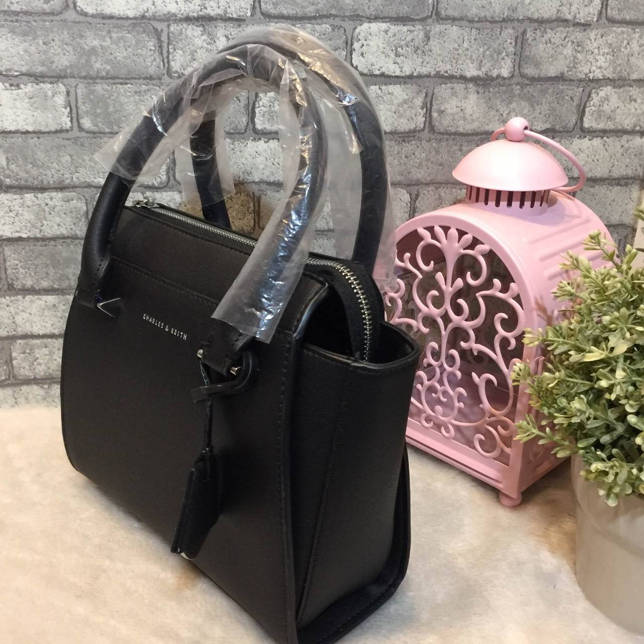CHARLES & KEITH MINI CITY BAG กระเป๋าถือหรือสะพาย ขนาดกะทัดรัด กำลังดี หนังpu เรียบ อยู่ทรงแข็ง เปิด-ปิดด้วยซิป ด้านหน้าห้อยประดับอะไหล่ปั๊มโลโก้ ดูเรียบหรู ภายในมีช่องซิปเล็ก 1 ช่อง มาพร้อมสายสะพายยาวปรับได้ ฐานมีหมุดรองฐานกันรอยสี่มุม สะพายสบายๆไปเที่ยว
