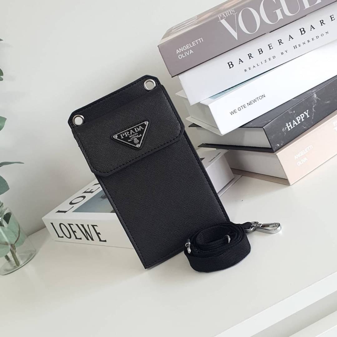PRADA PHONE CASE ไอเท็มสุดคลาสสิคที่ทุกท่านควรมี! Prada Saffiano Leather Smartphone Case งานพรีเมี่ยมกิ้ฟท์จากเคาเตอร์ต่างประเทศ ของมีจำนวนจำกัด หนังลาย saffiano อยู่ทรงสวย ดีไซน์หรูหรา ดูดี ทรงCrossbody ด้านหน้ามีโลโก้แบรนด์ อะไหล่ทอง ด้านในเปิดปิดด้วยกร