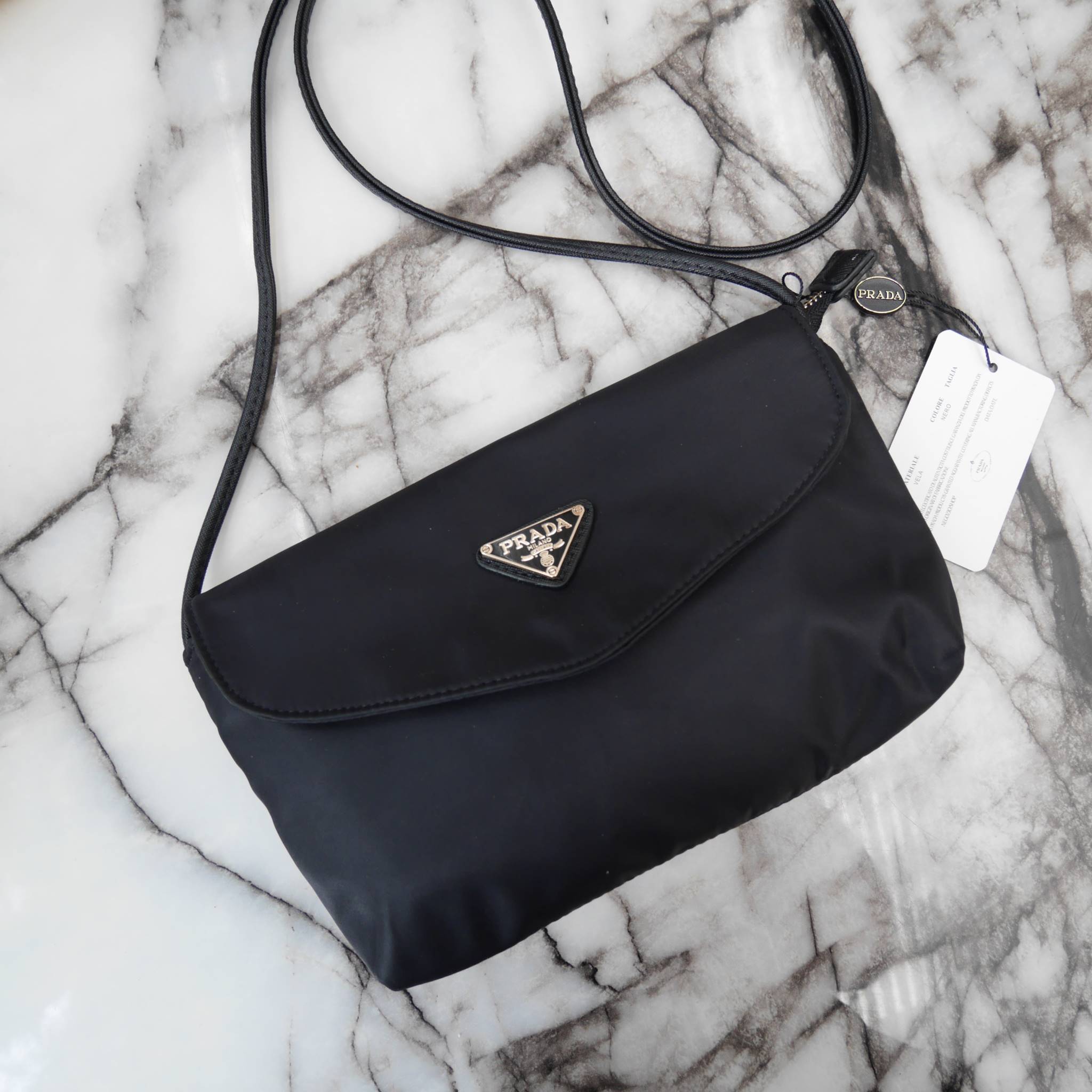 Best Seller! จากงานพรีเมี่ยมกิ้ฟ จากเคาเตอร์ต่างประเทศ จากแบรนด์ PRADA ค่า เป็น กระเป๋าผ้าไนล่อน ตามแบบฉบับของแบรนด์เลย ใบนี้มีสายยาวให้คะ เลิศมาก สะพายเป็น shoulder bag ได้เลย ขนาดกำลังดีคะ ตัวกระเป๋าเบามาก ใส่มือถือได้ทุกรุ่น ใช้แล้วสวยมากๆ อะไหล่ทองหรู