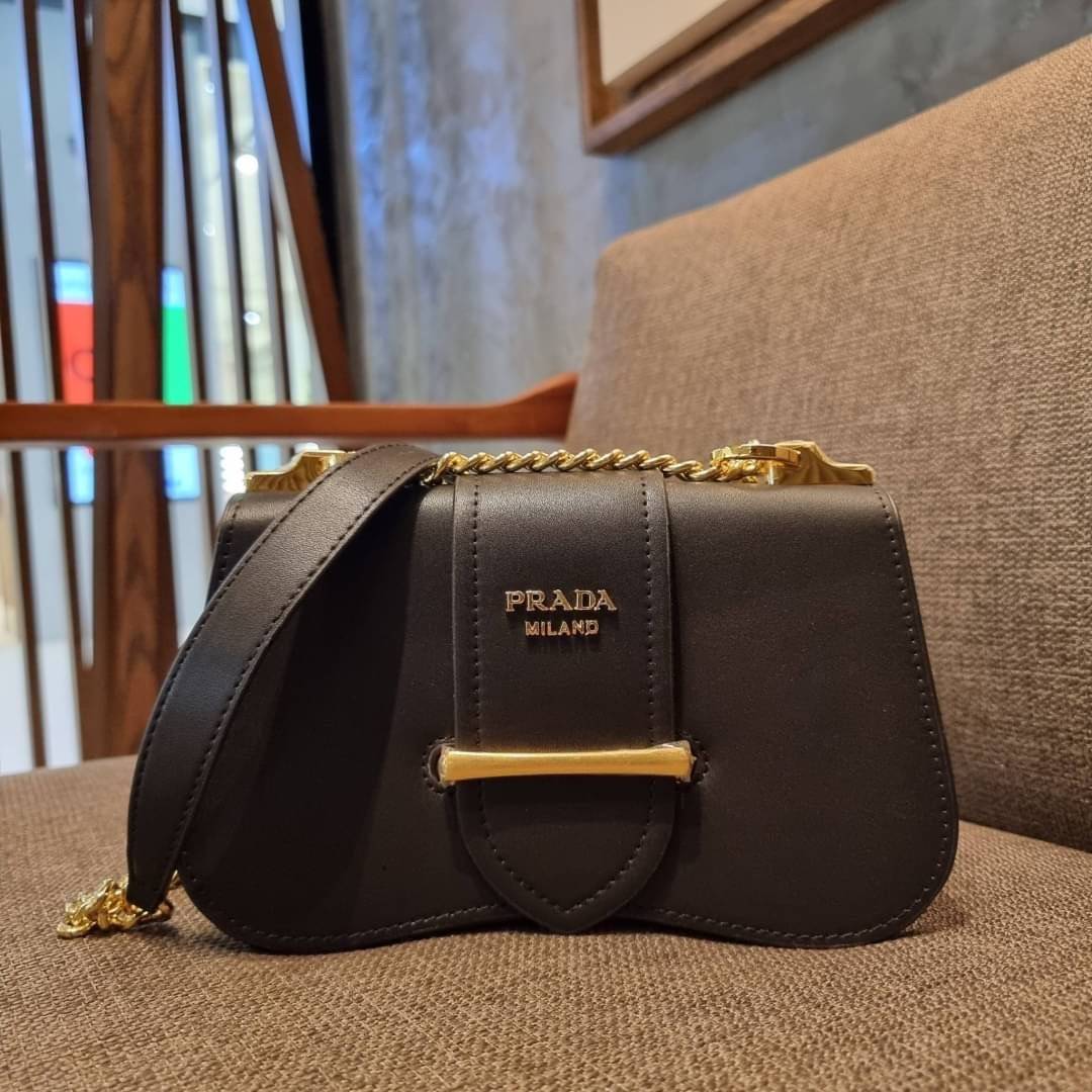 PRADA FRAGRANCE SHOULDER BAG WITH GWP ไอเท็มสุดโปรดที่ควรค่าแก่การครอบครองและเก็บสะสม กระเป๋าสะพายไหล่ สวยคม สีดำคลาสสิคตัดกับอะไหล่ทองเป็นอย่างดี วัสดุหนังแท้เต็มใบ เปิดปิดด้วยแถบหนังสอดในช่อง ใช้งานสะดวก พกพาง่าย ขนาดกำลังสวย สายสะพายในตัว สะพายได้หลากห